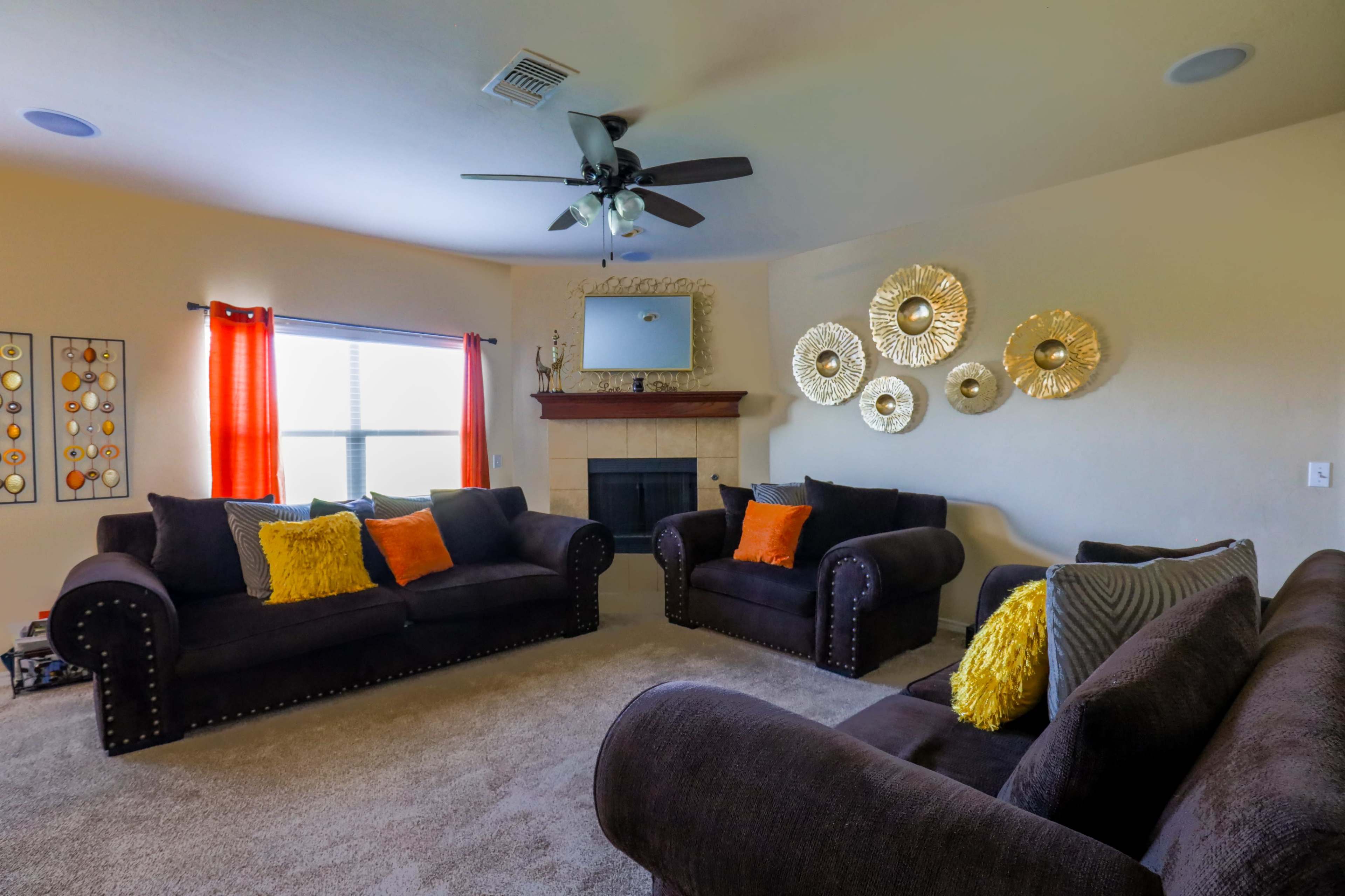 The living room features two dark sofas with decorative pillows, a coffee table, a fireplace, and a wall adorned with metallic circular decor.