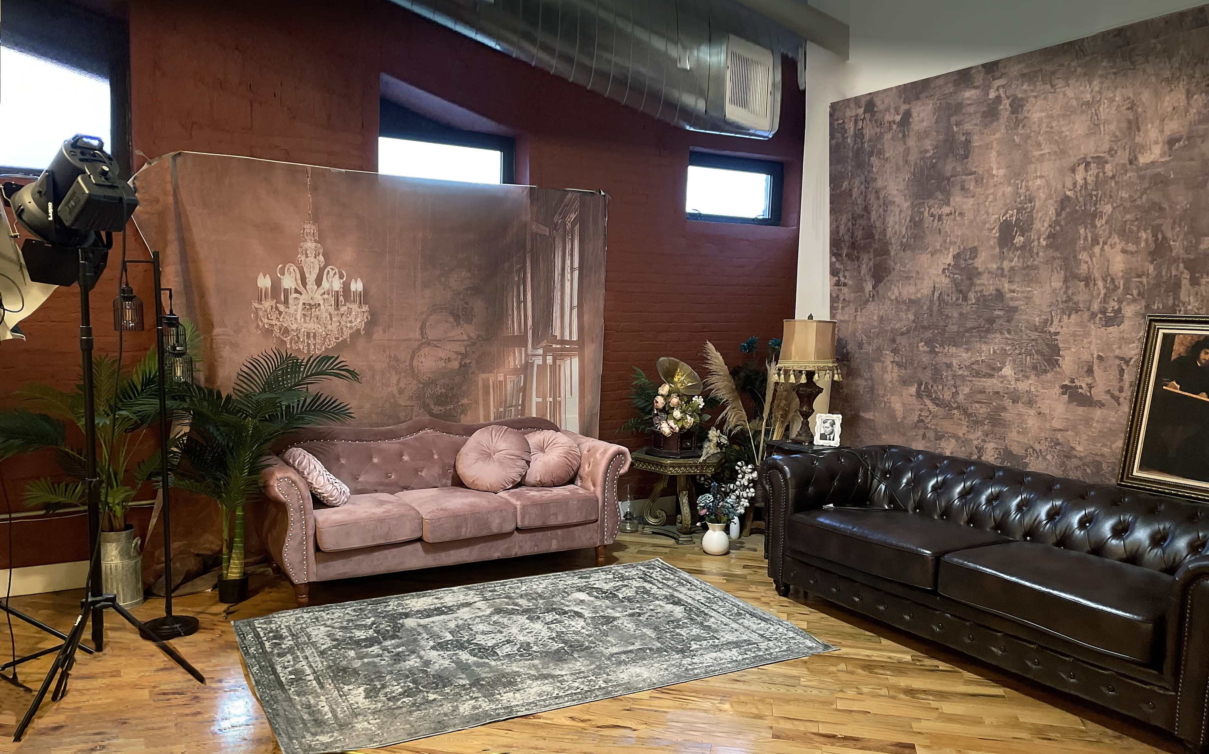 The image shows a photography studio with two sofas, a decorative backdrop, a rug, and various ornamental pieces.