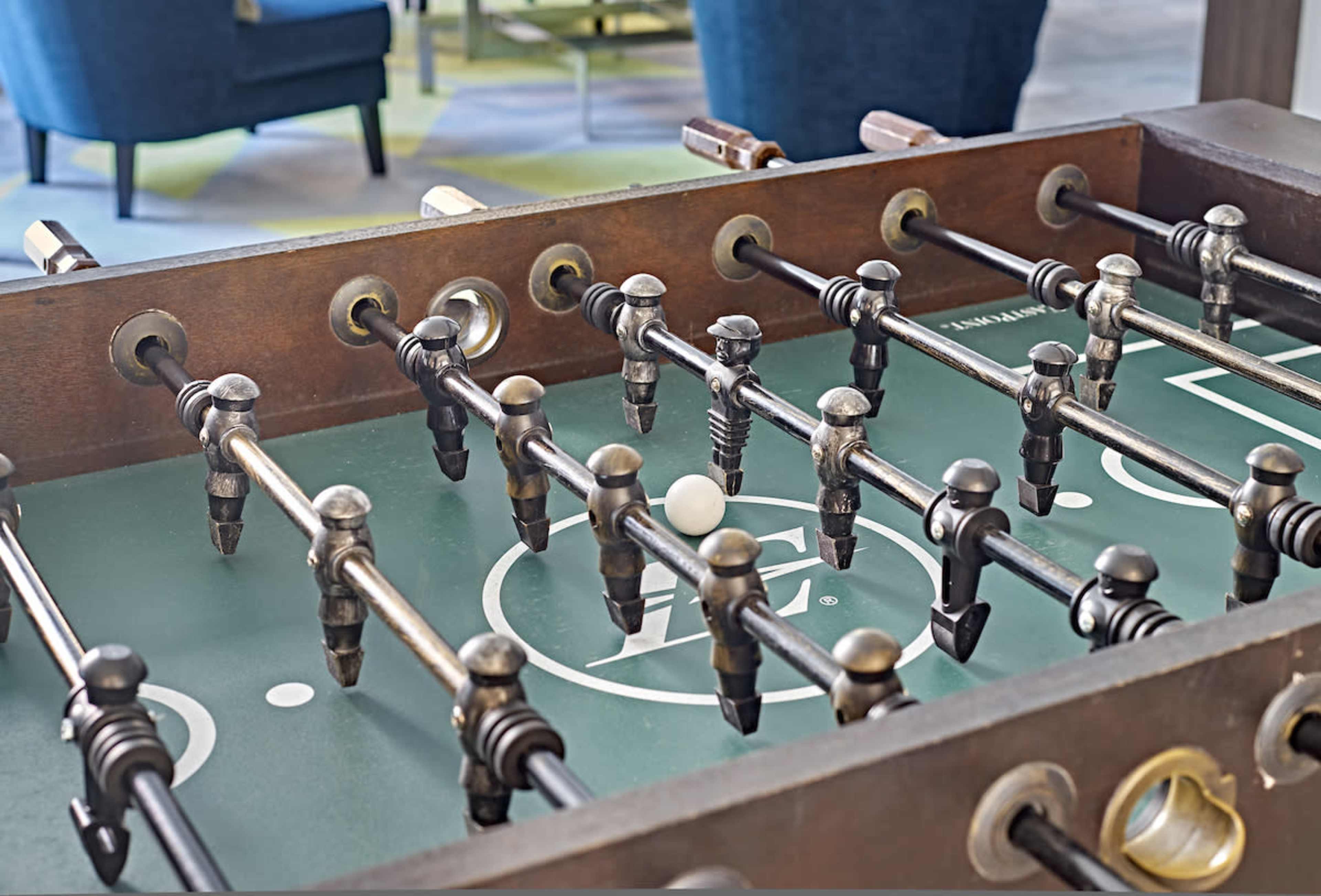 A foosball table with a white ball positioned near the center and various players lined up on metal rods.