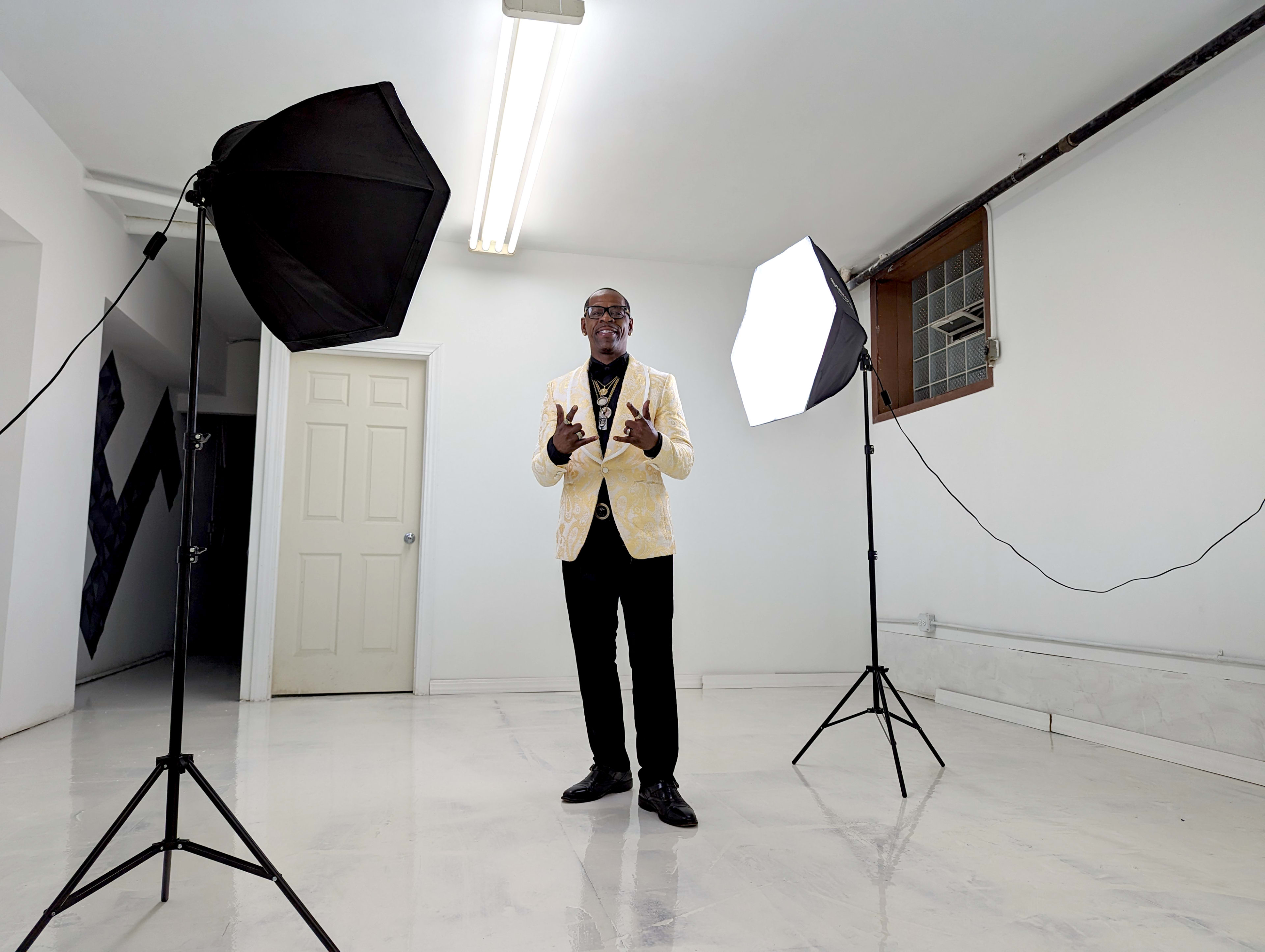 A person stands in a well-lit studio space between two softbox lights, facing the camera.