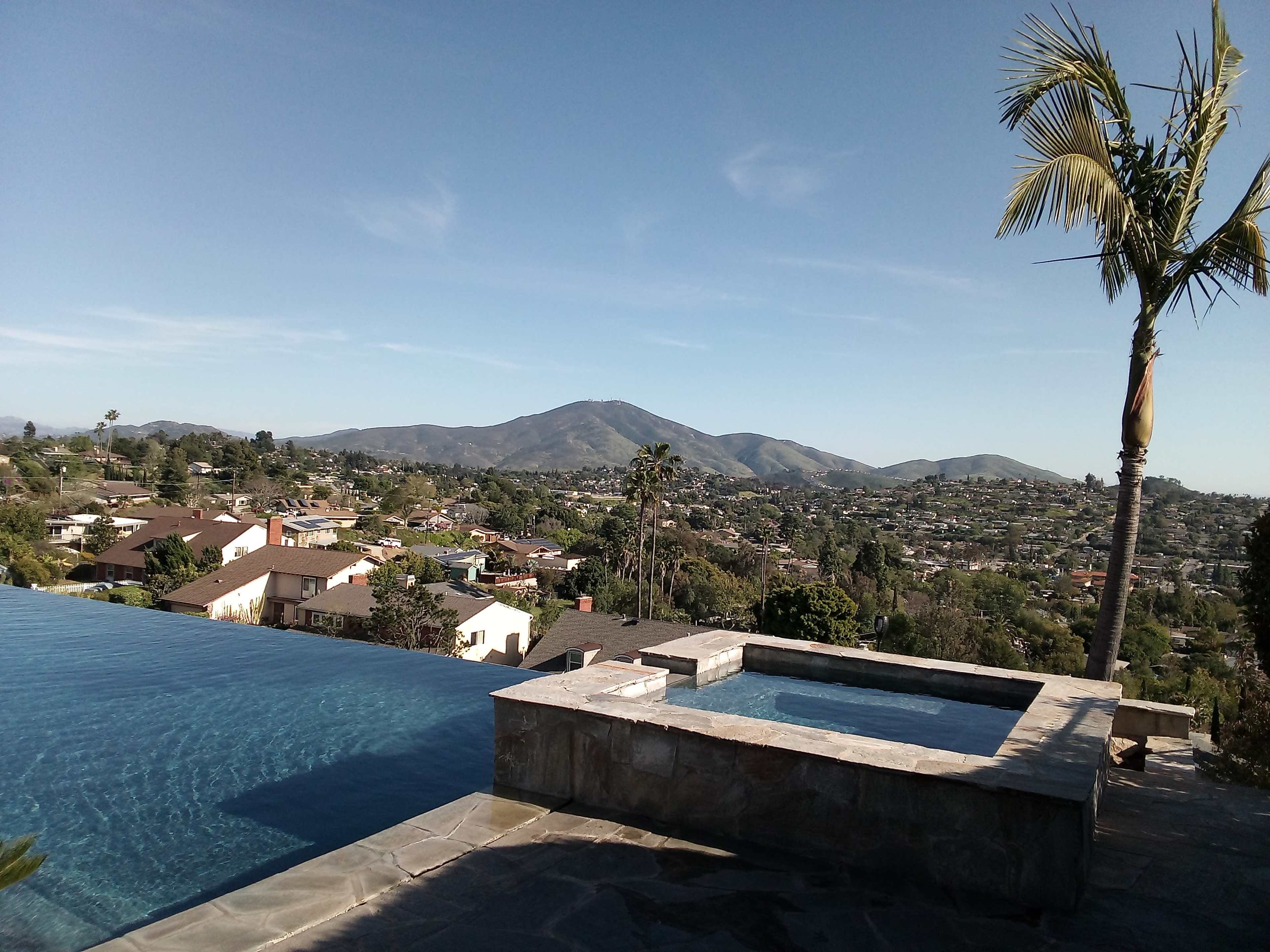 An infinity pool overlooking a mountainous landscape and suburban homes.
