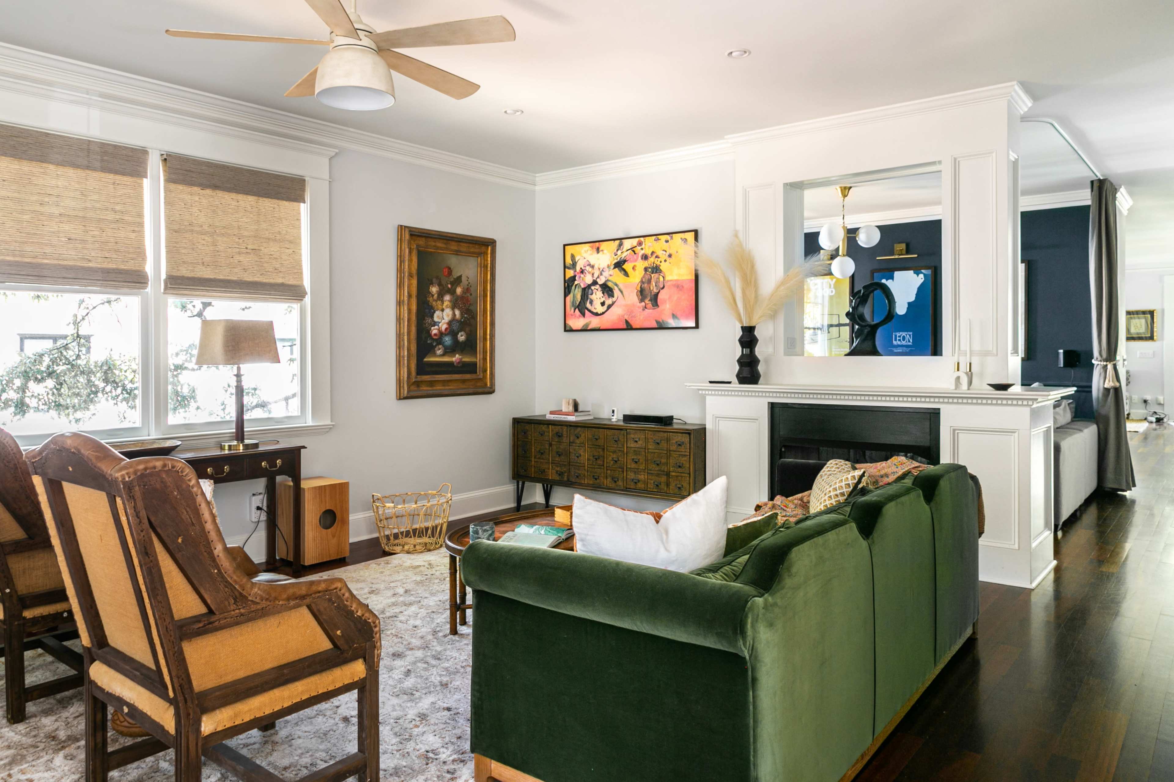 The living room features a green sofa, two wooden chairs, a coffee table, and a wall-mounted television above a fireplace.
