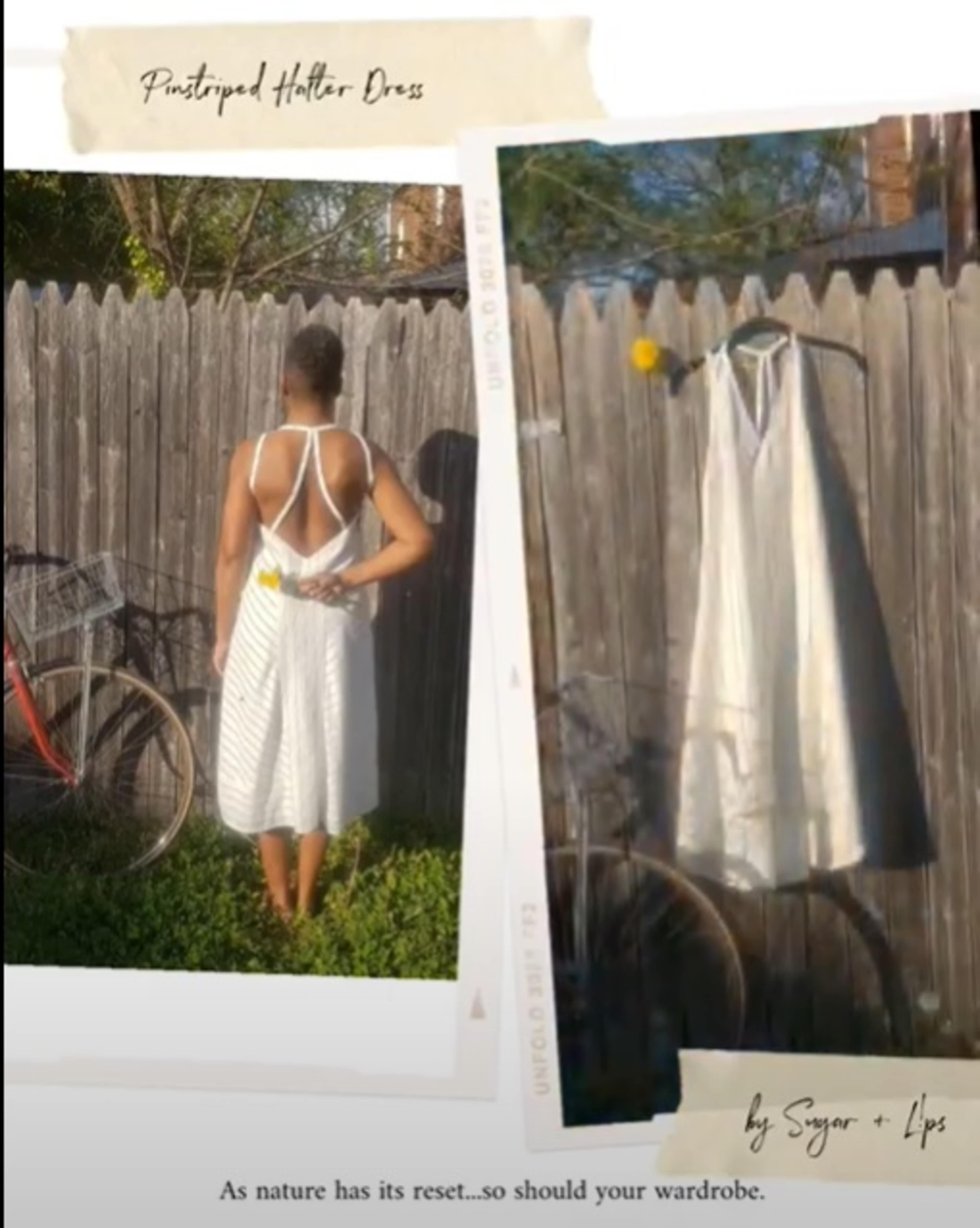 A person stands in a striped halter dress against a wooden fence with a bicycle nearby.