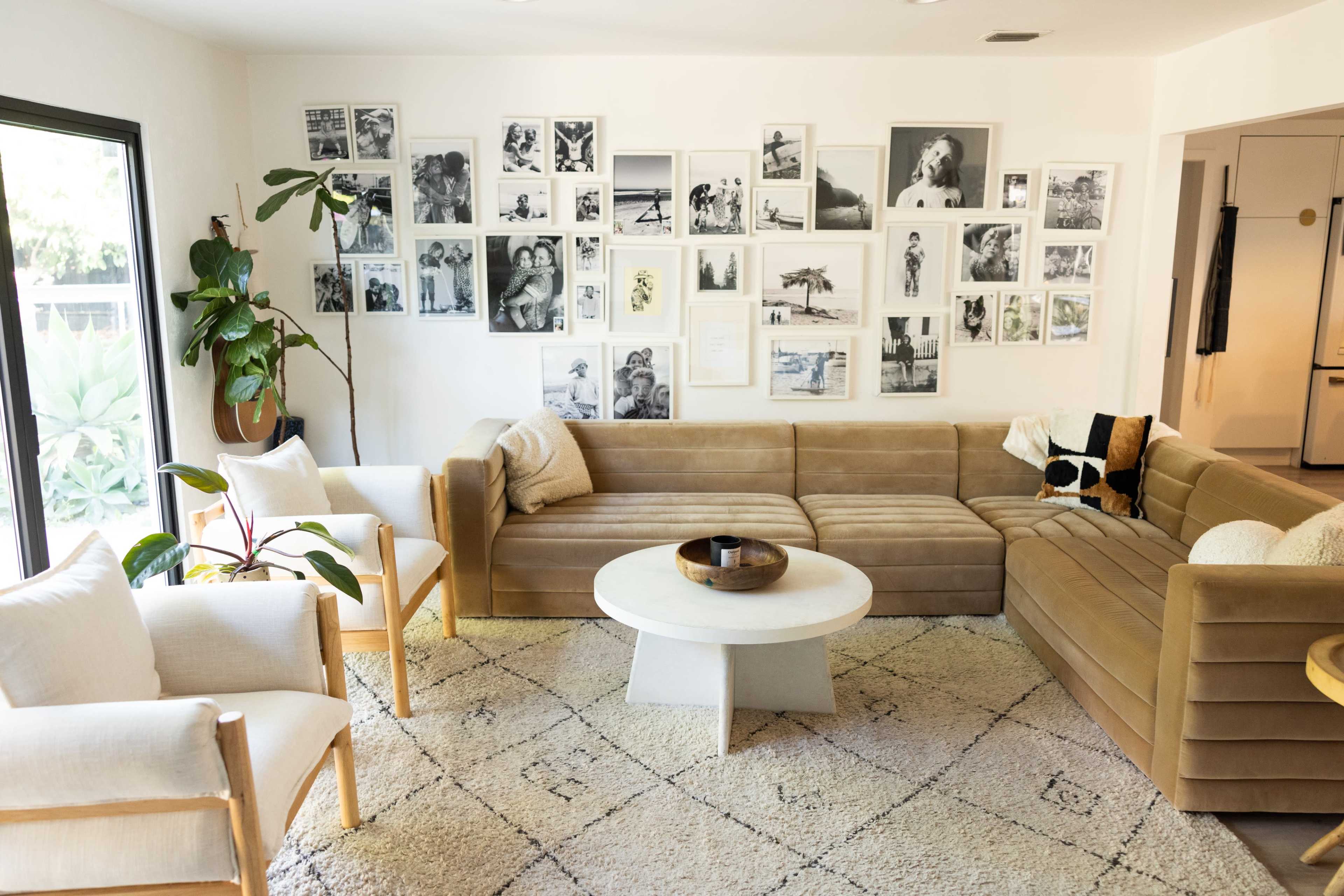 A modern living room features a sectional sofa, a round coffee table, and walls adorned with black-and-white photographs.