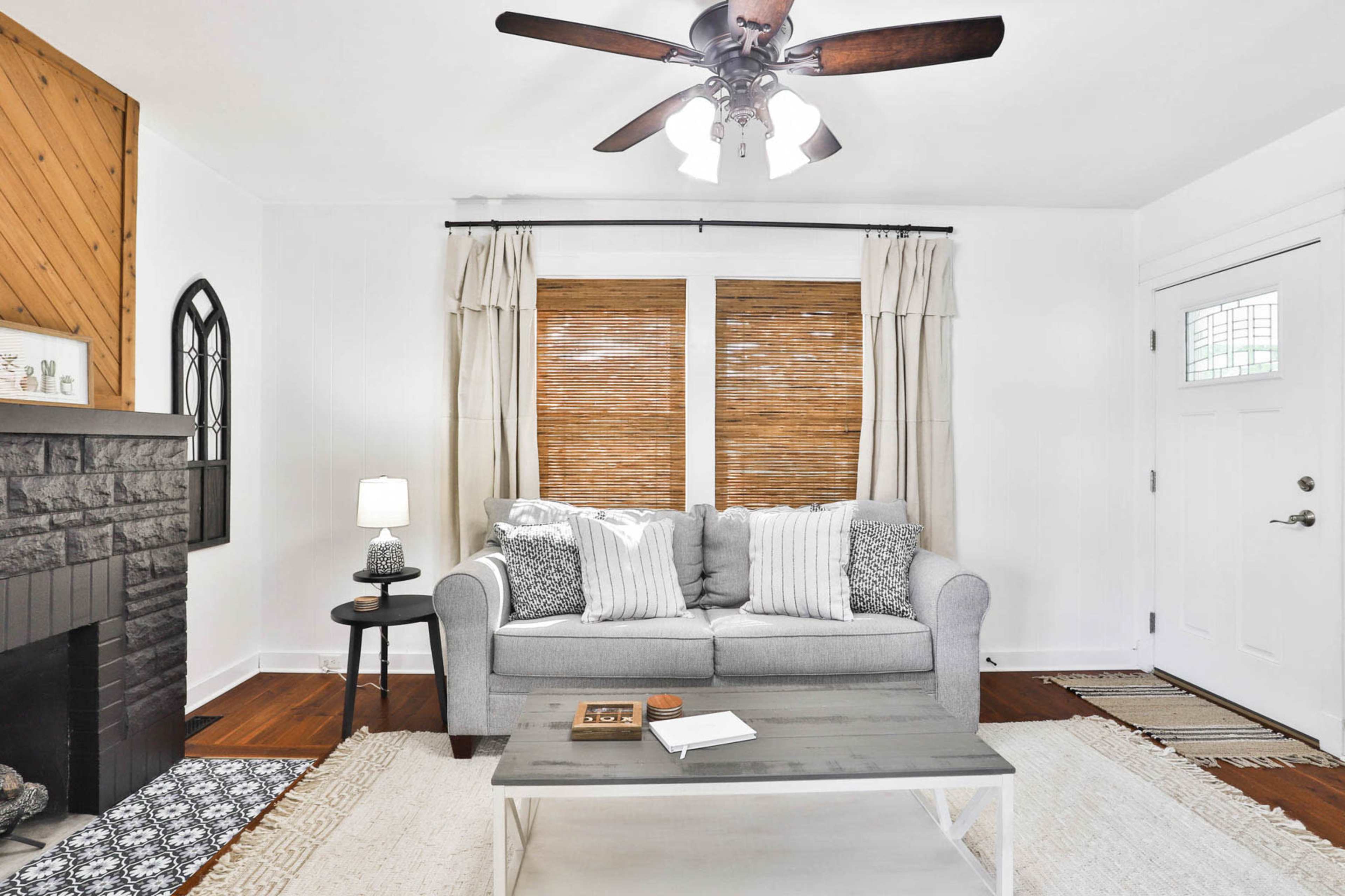 A living room with a gray sofa, a coffee table, and wooden window blinds.