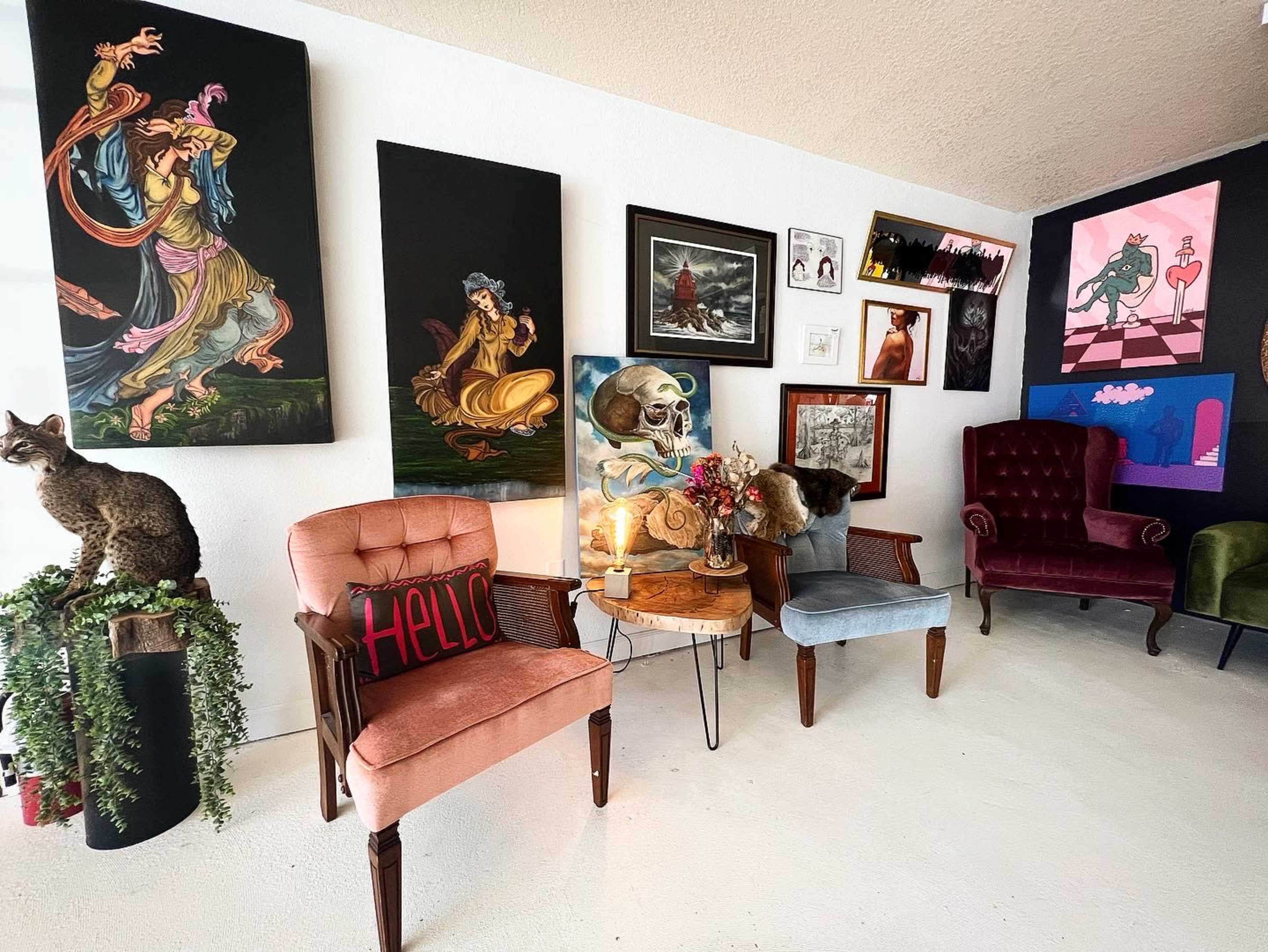 An eclectic seating area with various styled chairs, decorated walls featuring multiple artworks, and a small table with decorative items.