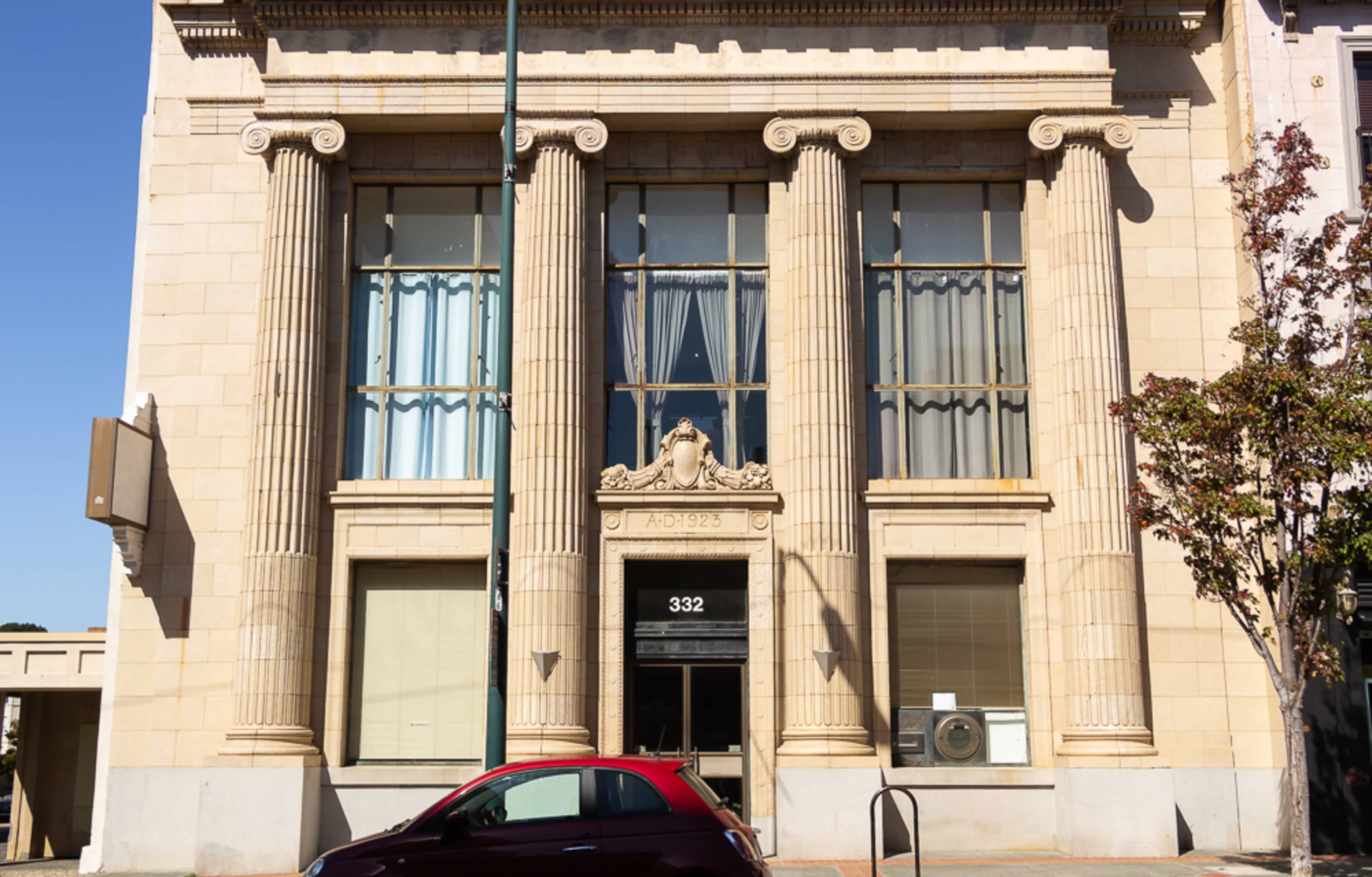 A classical-style building with tall columns, large windows, and a decorative facade, located at 332.