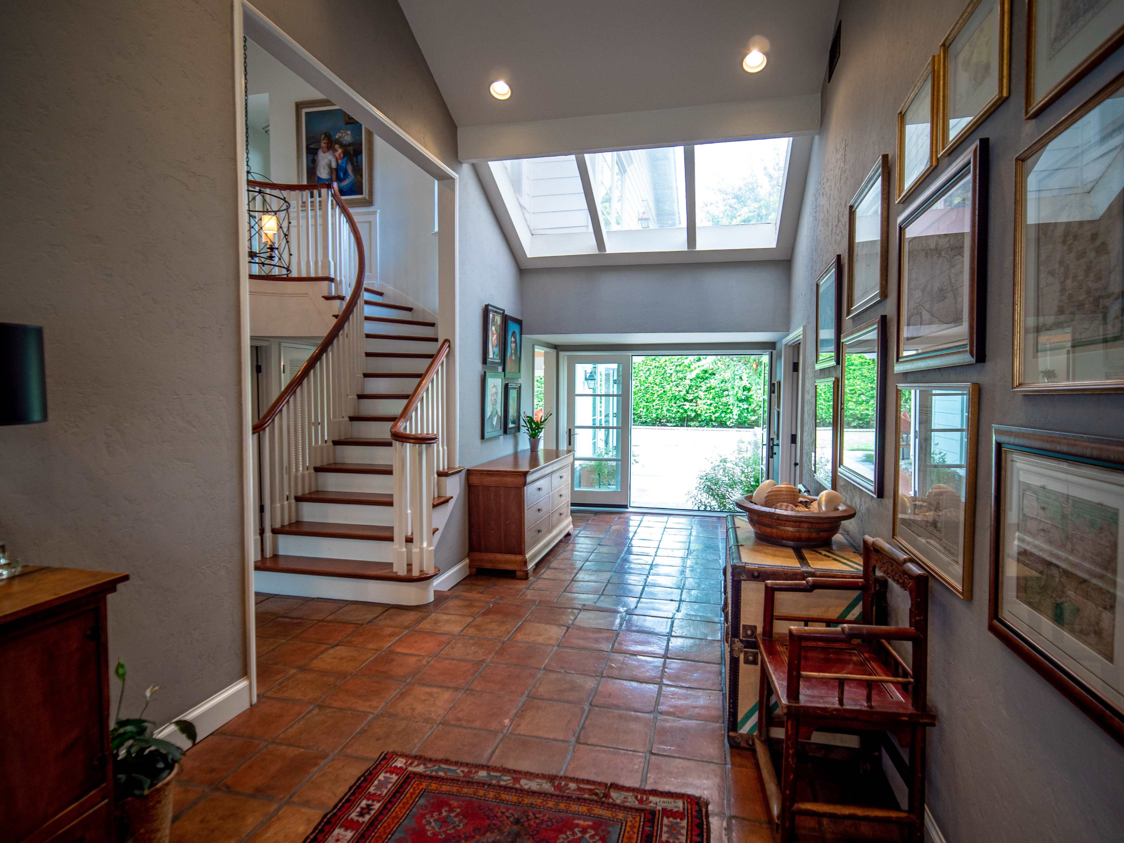 A spacious entryway featuring a staircase, tiled flooring, and walls adorned with framed artwork.