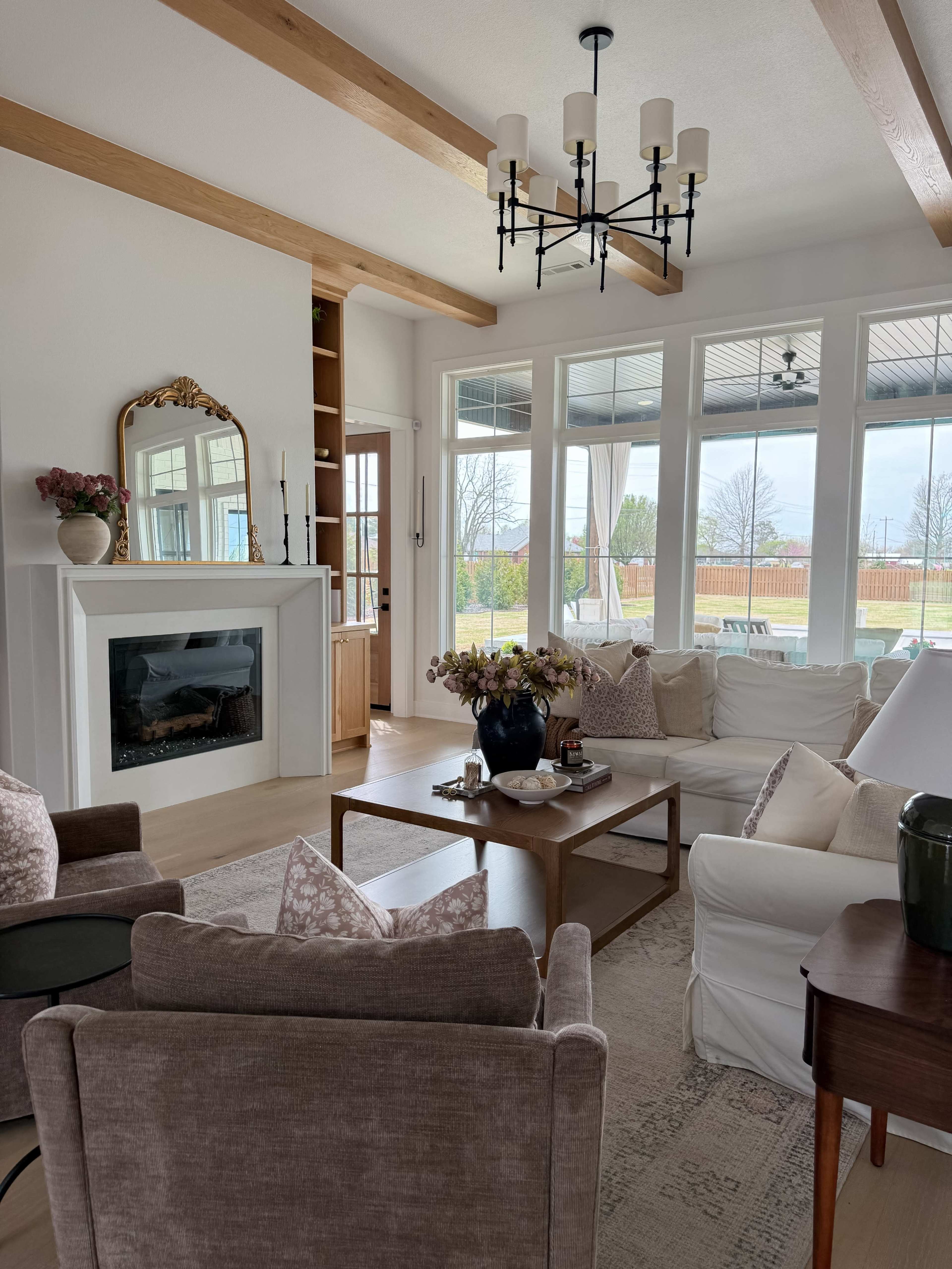 The image depicts a cozy living room with large windows, a fireplace, and comfortable seating arranged around a coffee table.
