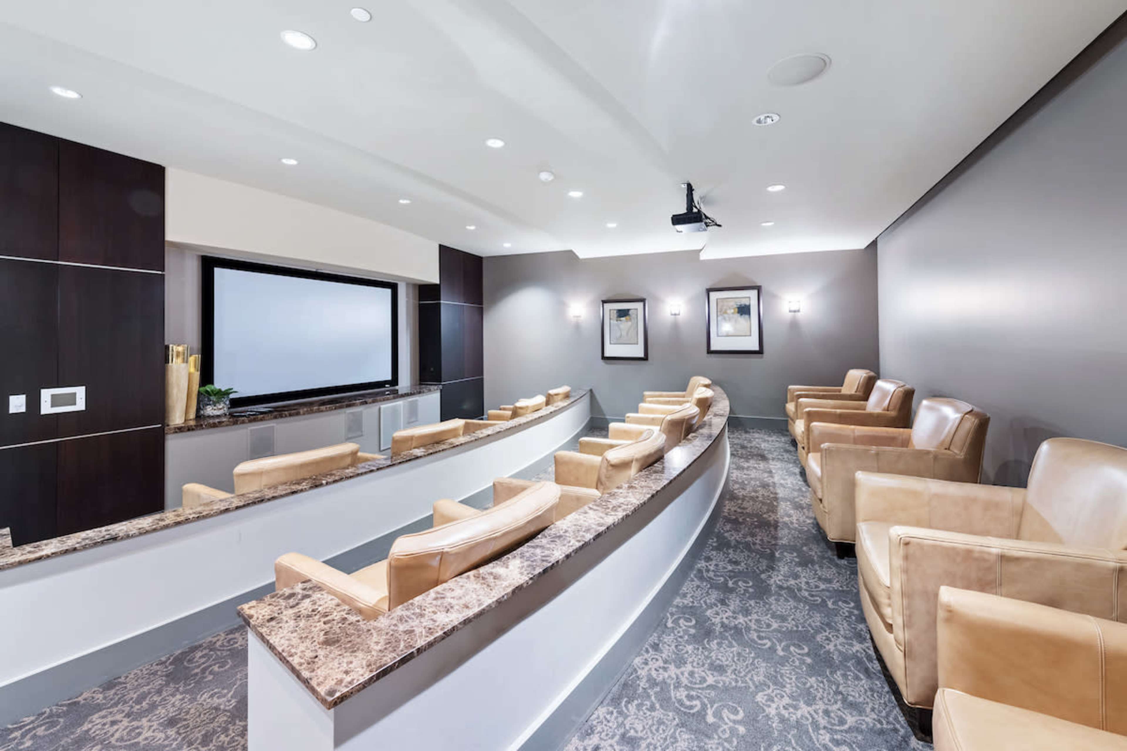 A modern conference room with tiered seating, a large screen, and framed artwork on the walls.