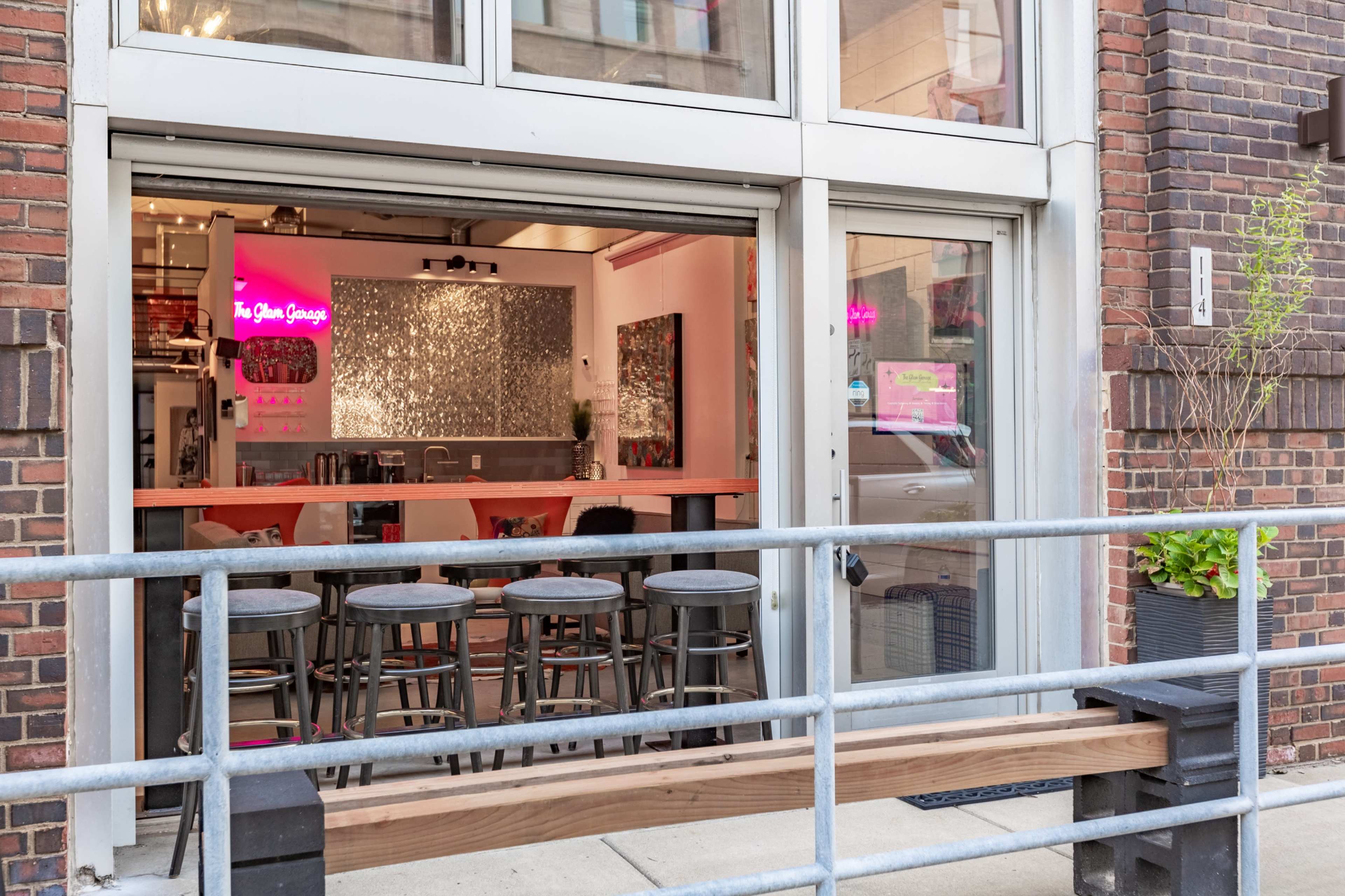 The image shows an open storefront with a seating area and a brightly lit interior featuring modern decor and a counter.