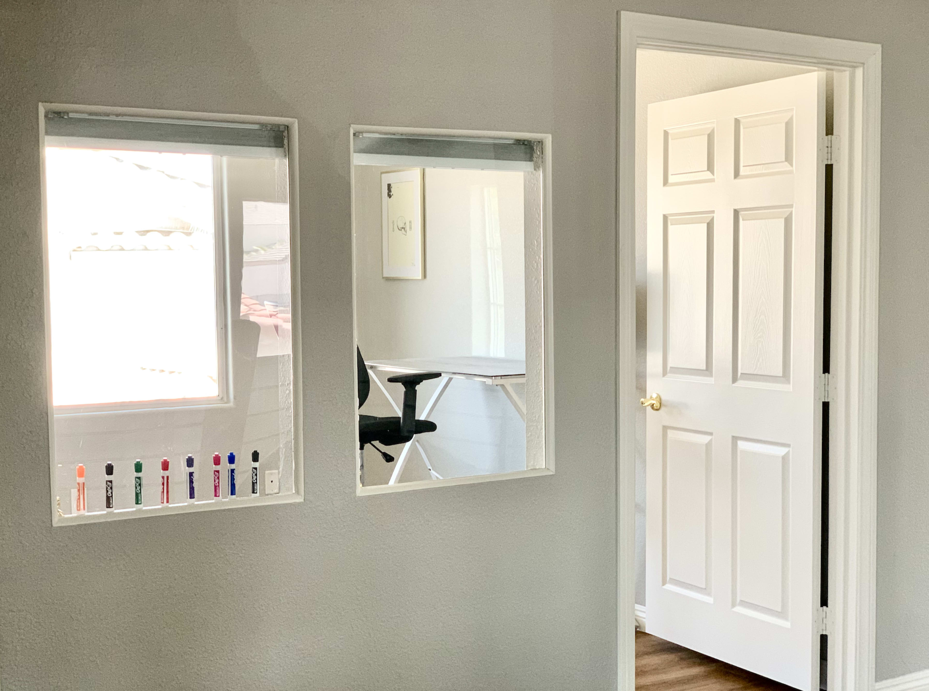 A light-colored room with two rectangular mirrors and a door leading to another space.