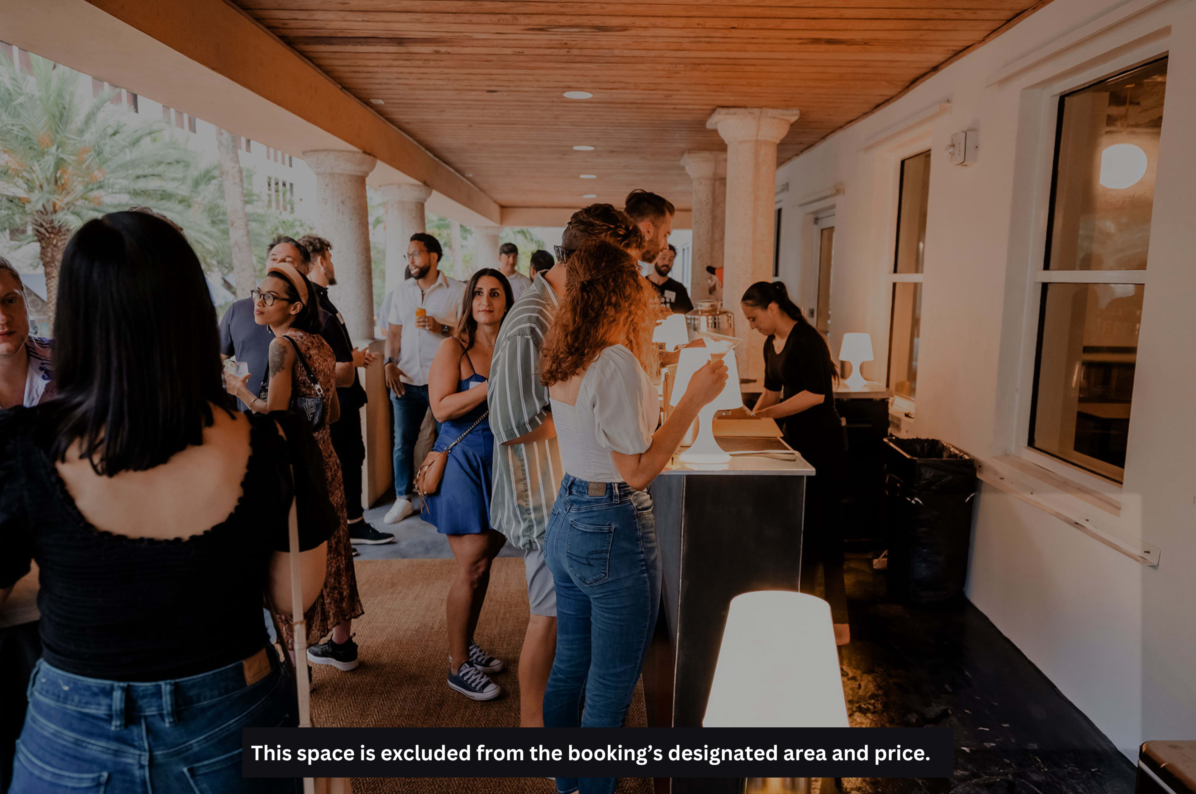 A group of people are gathered at a reception area with a counter, engaged in conversation and checking in for an event.