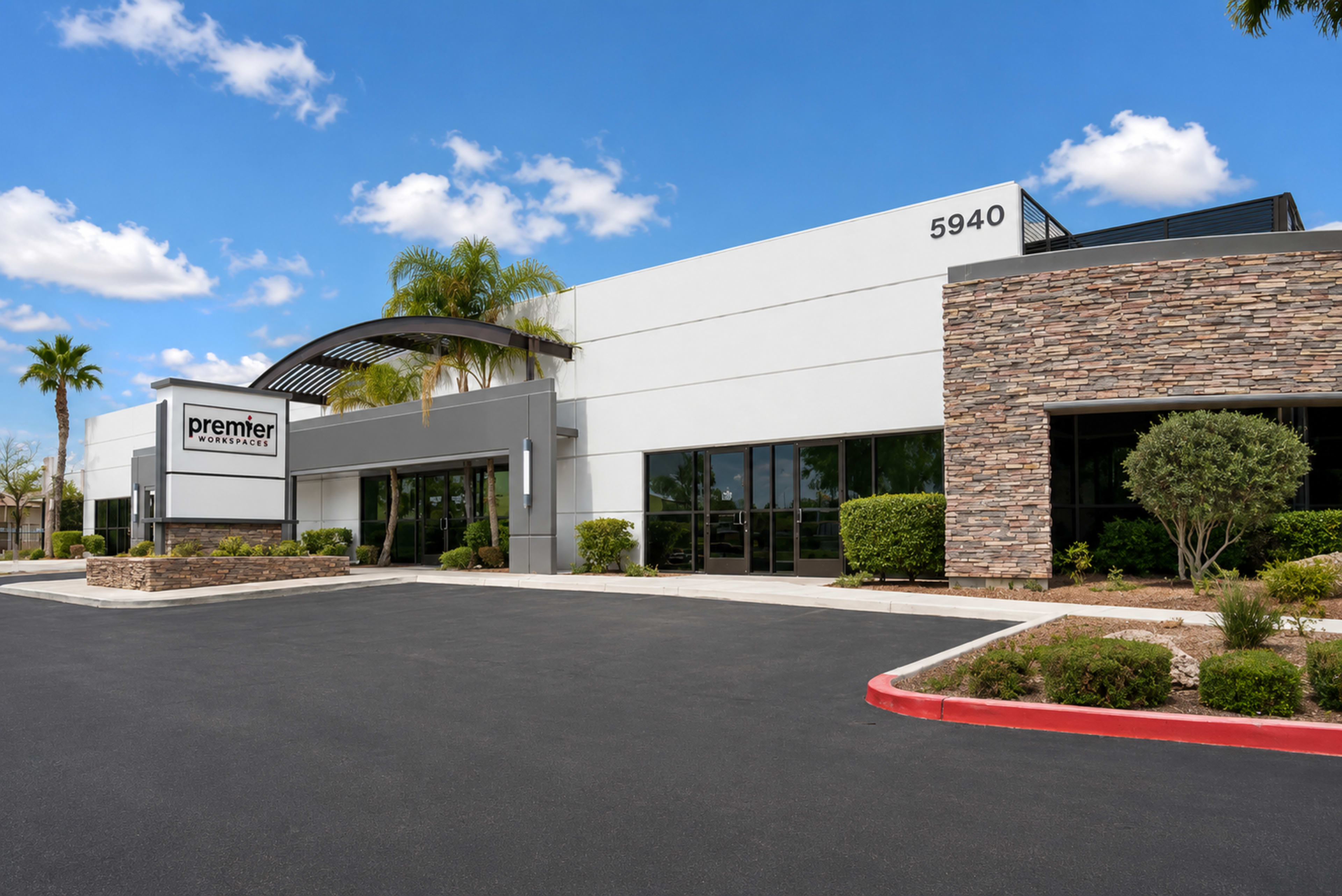The image shows a modern commercial building with a stone-accented facade, featuring a prominent sign for "premier" and surrounded by landscaped greenery.