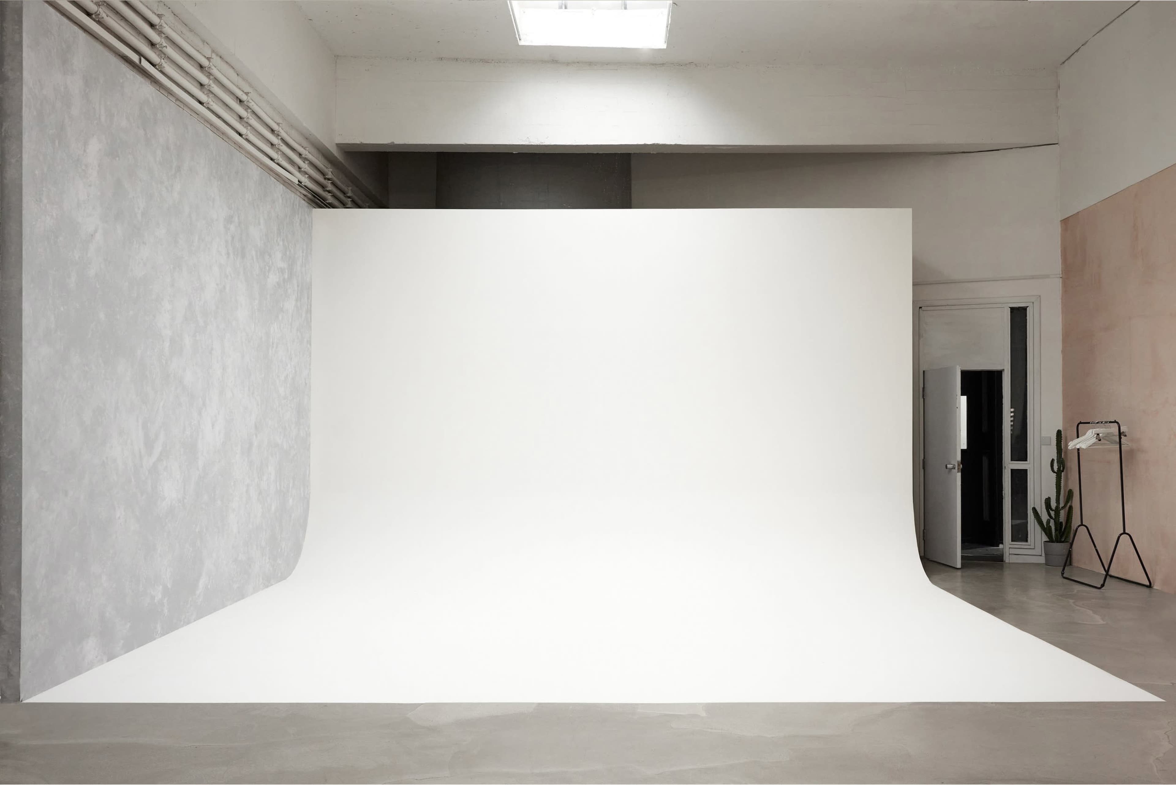 A minimally designed studio space with a large white backdrop and a smooth floor.