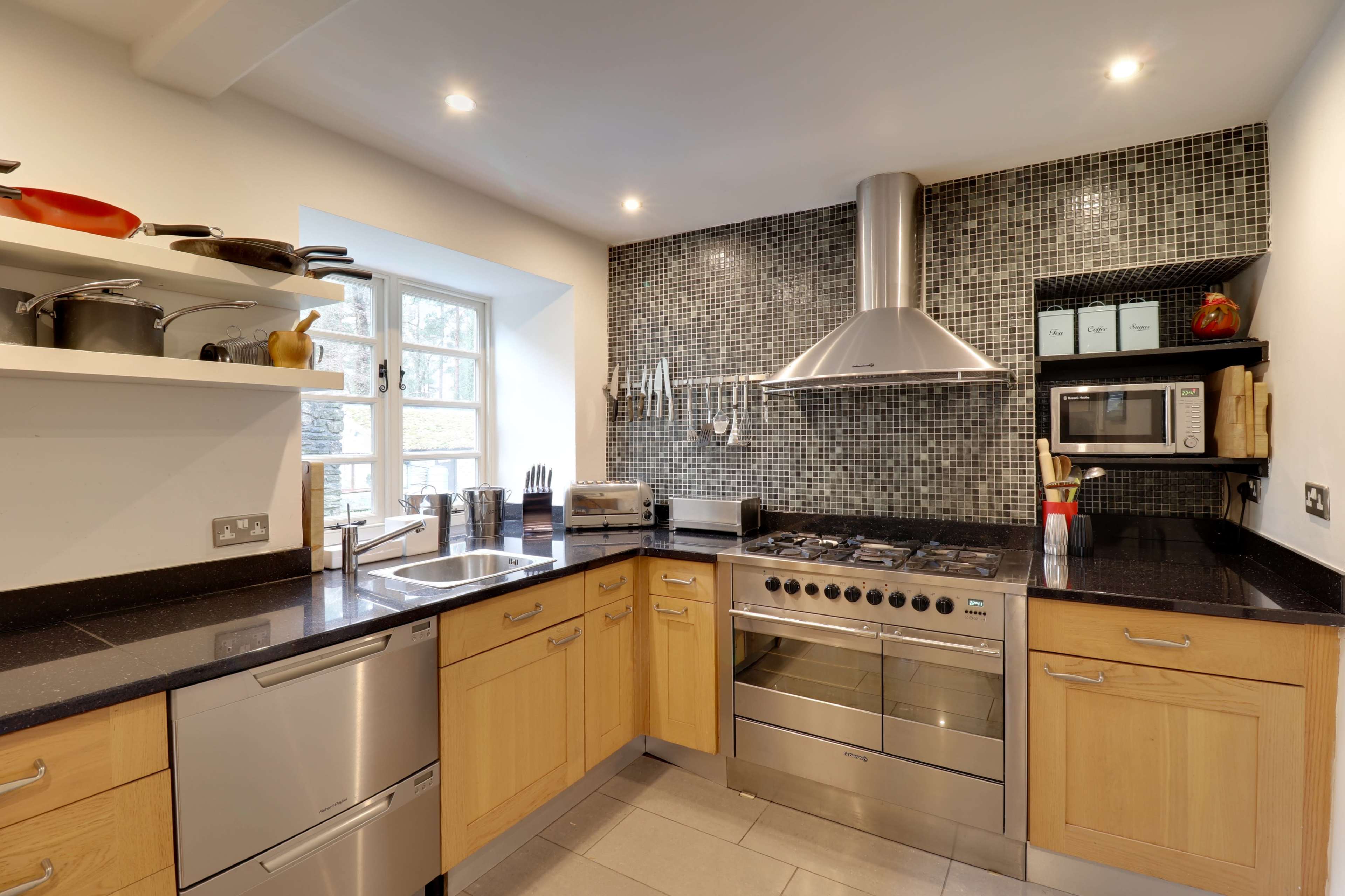A modern kitchen features wooden cabinets, a stainless steel stove, and a mosaic tile backsplash.