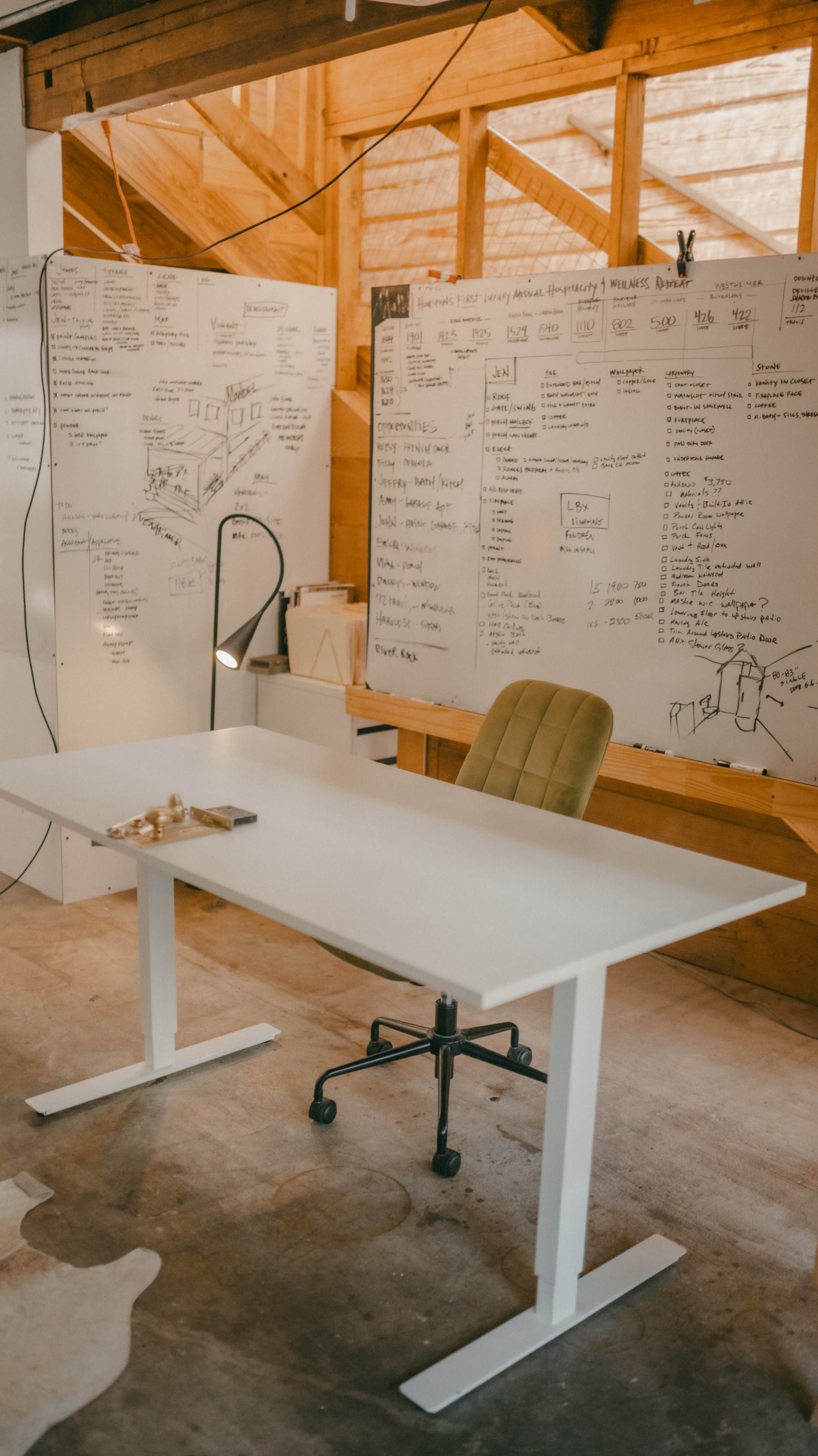 A minimalist office space features a white desk and a green swivel chair, set against walls covered in handwritten notes and diagrams.