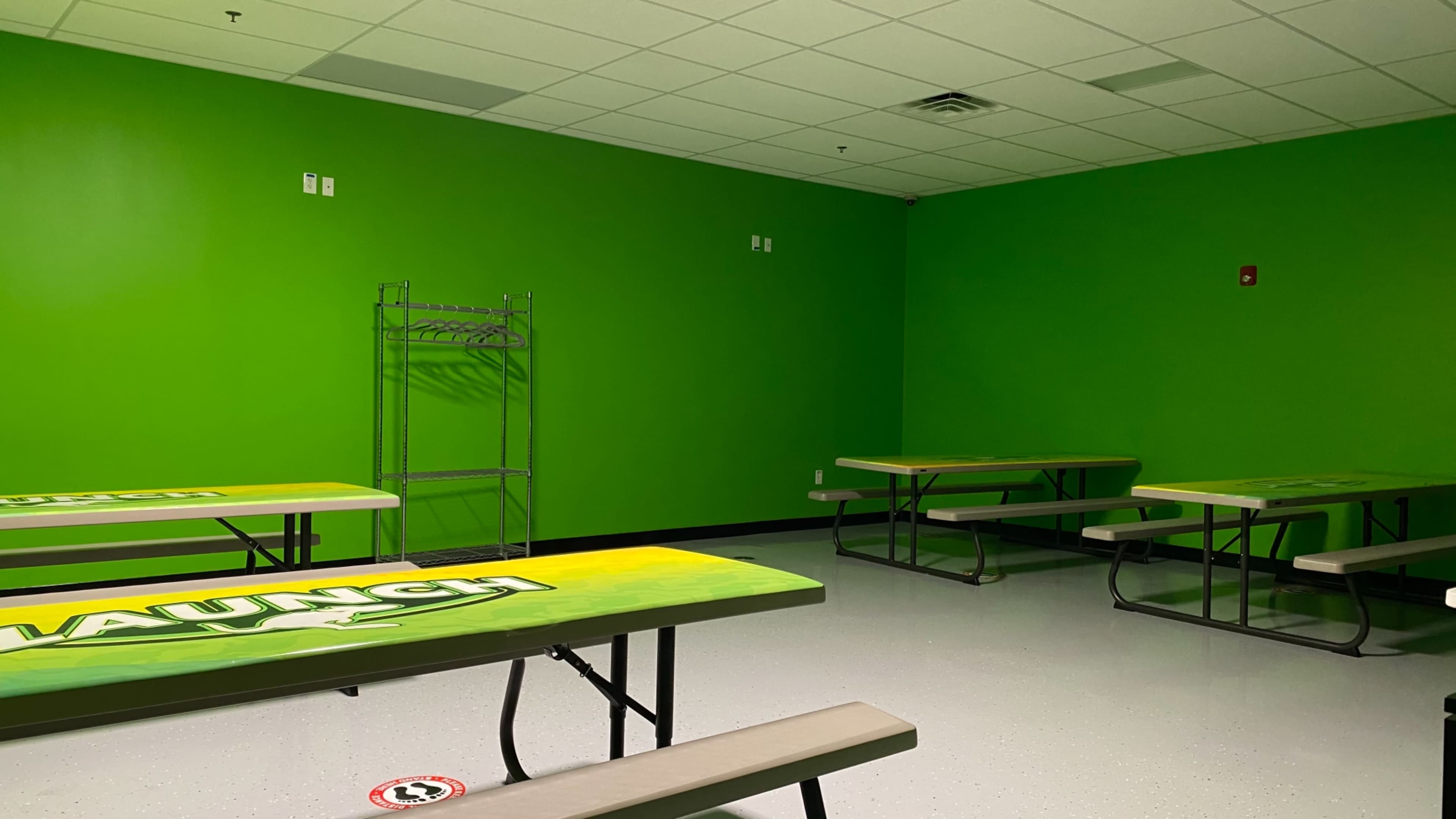 A vacant room with bright green walls and several folding tables arranged around the space.