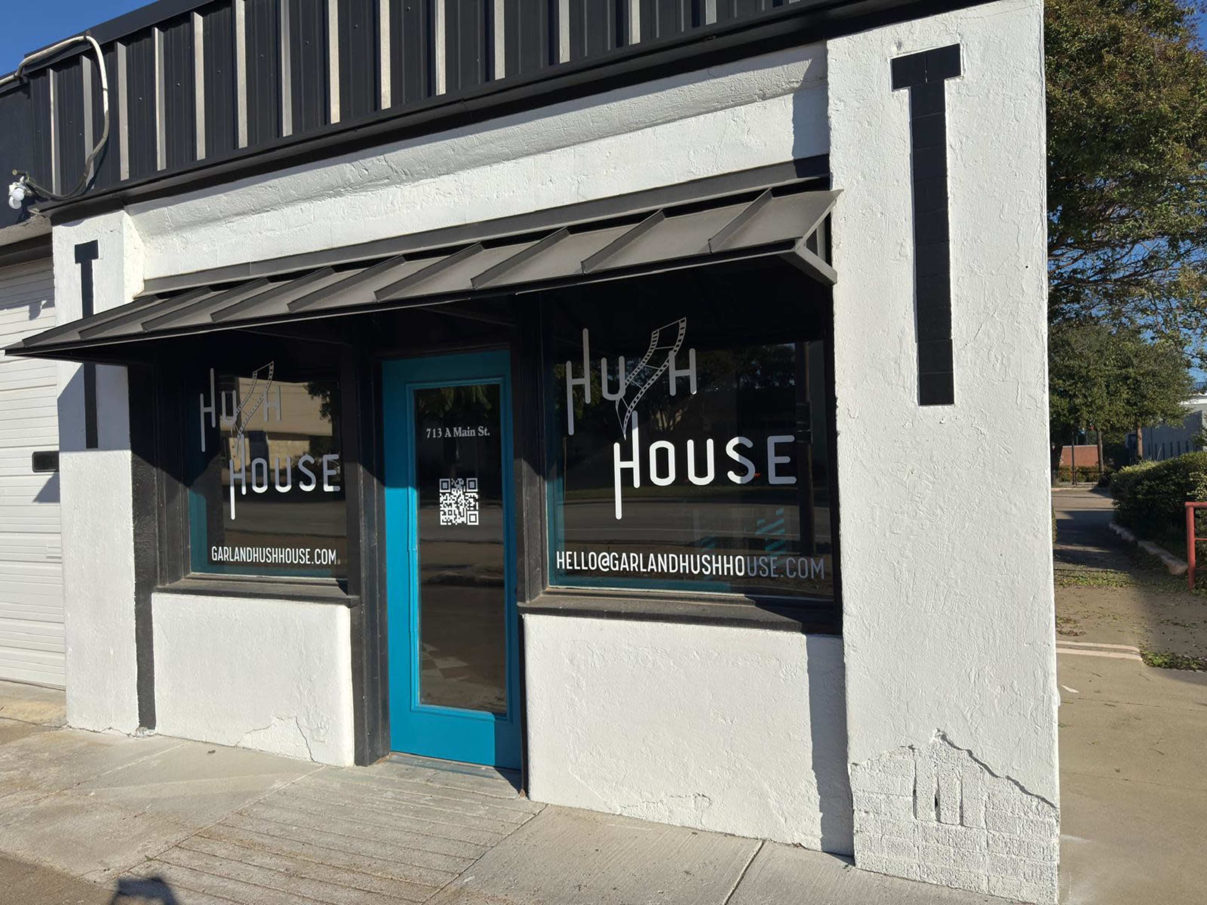 The image shows the exterior of a business with large windows displaying the name "Hugh House" and a teal door.