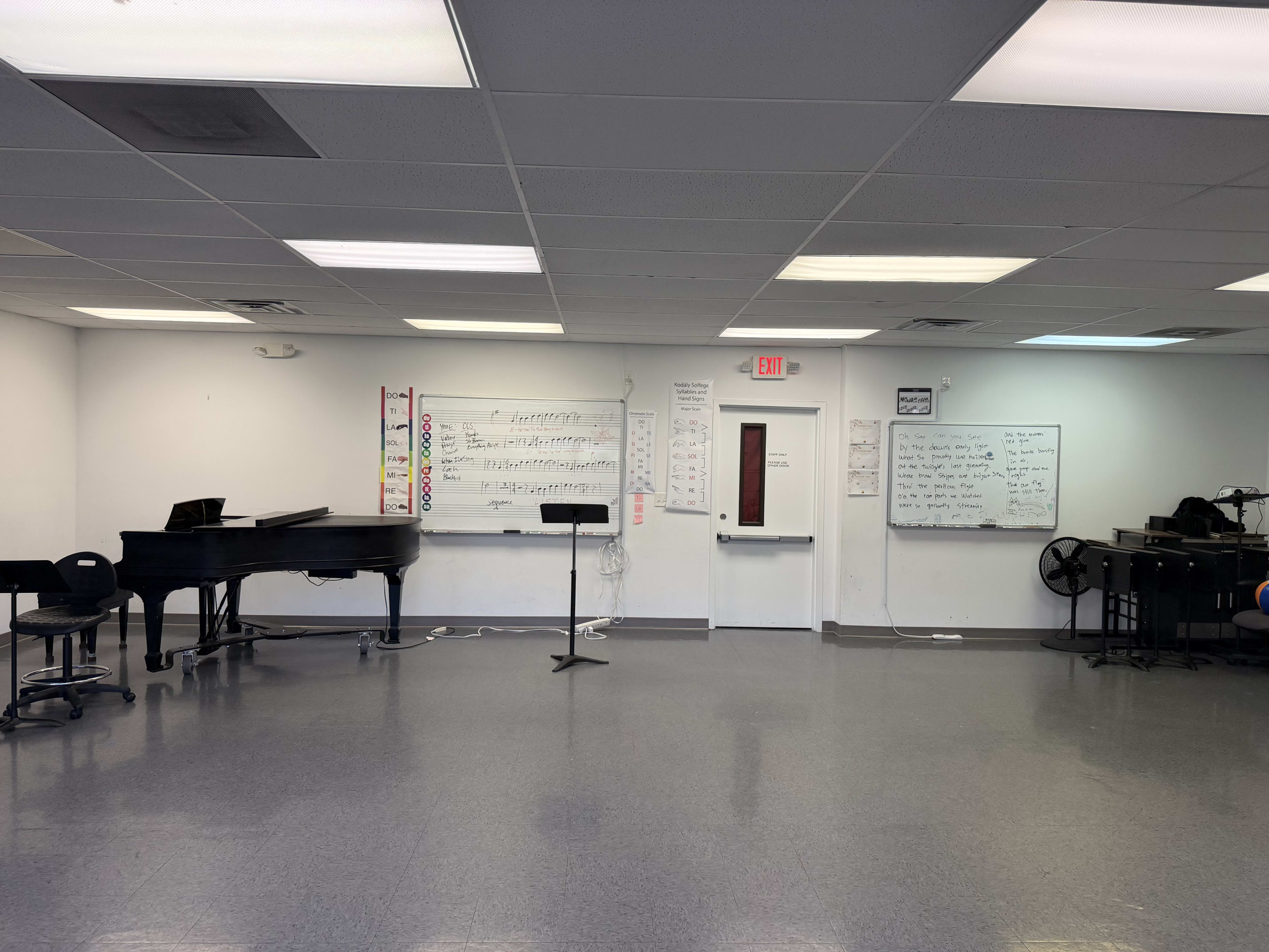 The image shows a music room with a grand piano, music stand, and various music-related notes displayed on the walls.