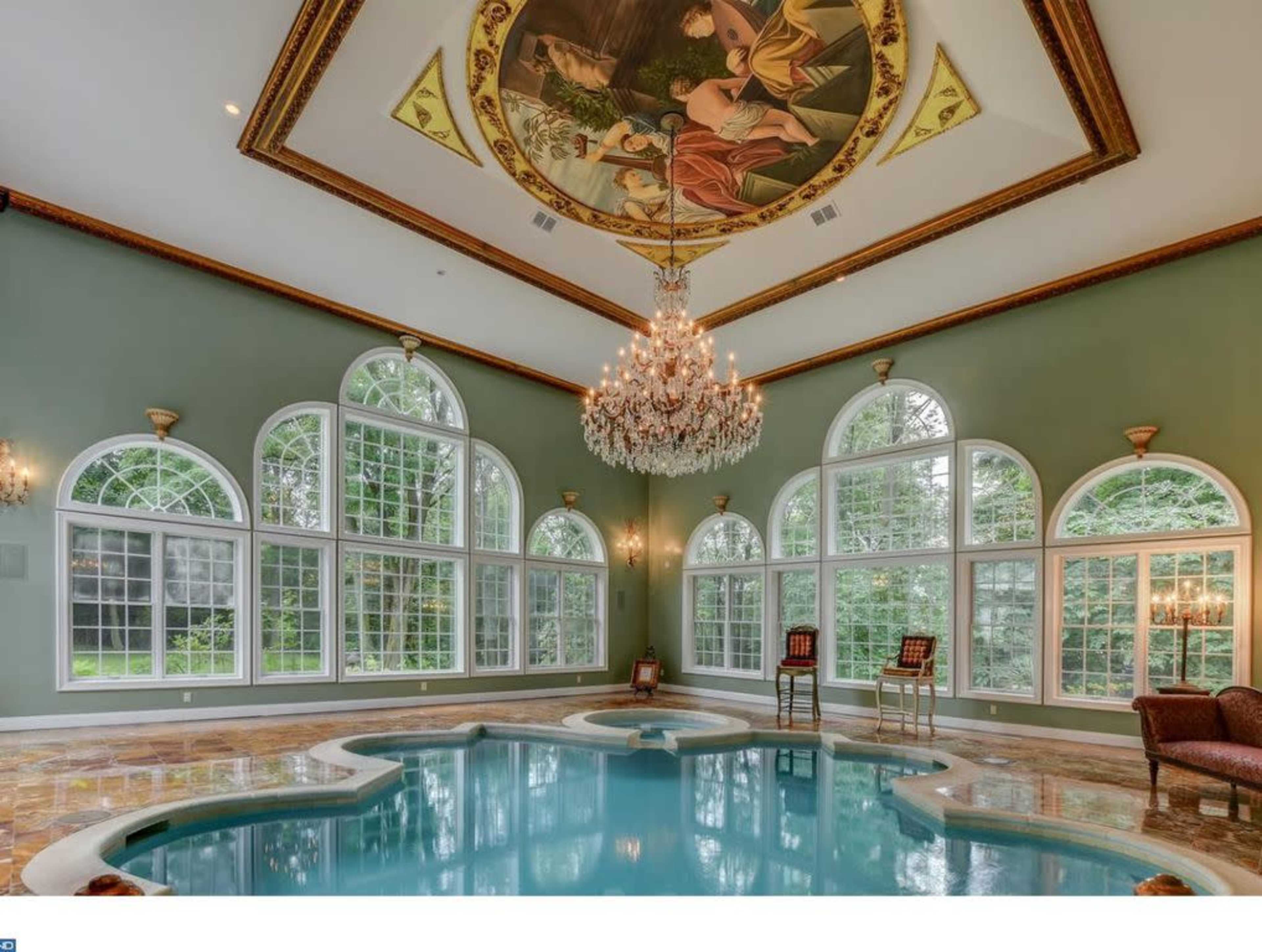 An indoor swimming pool with a decorative ceiling and large windows that provide natural light.
