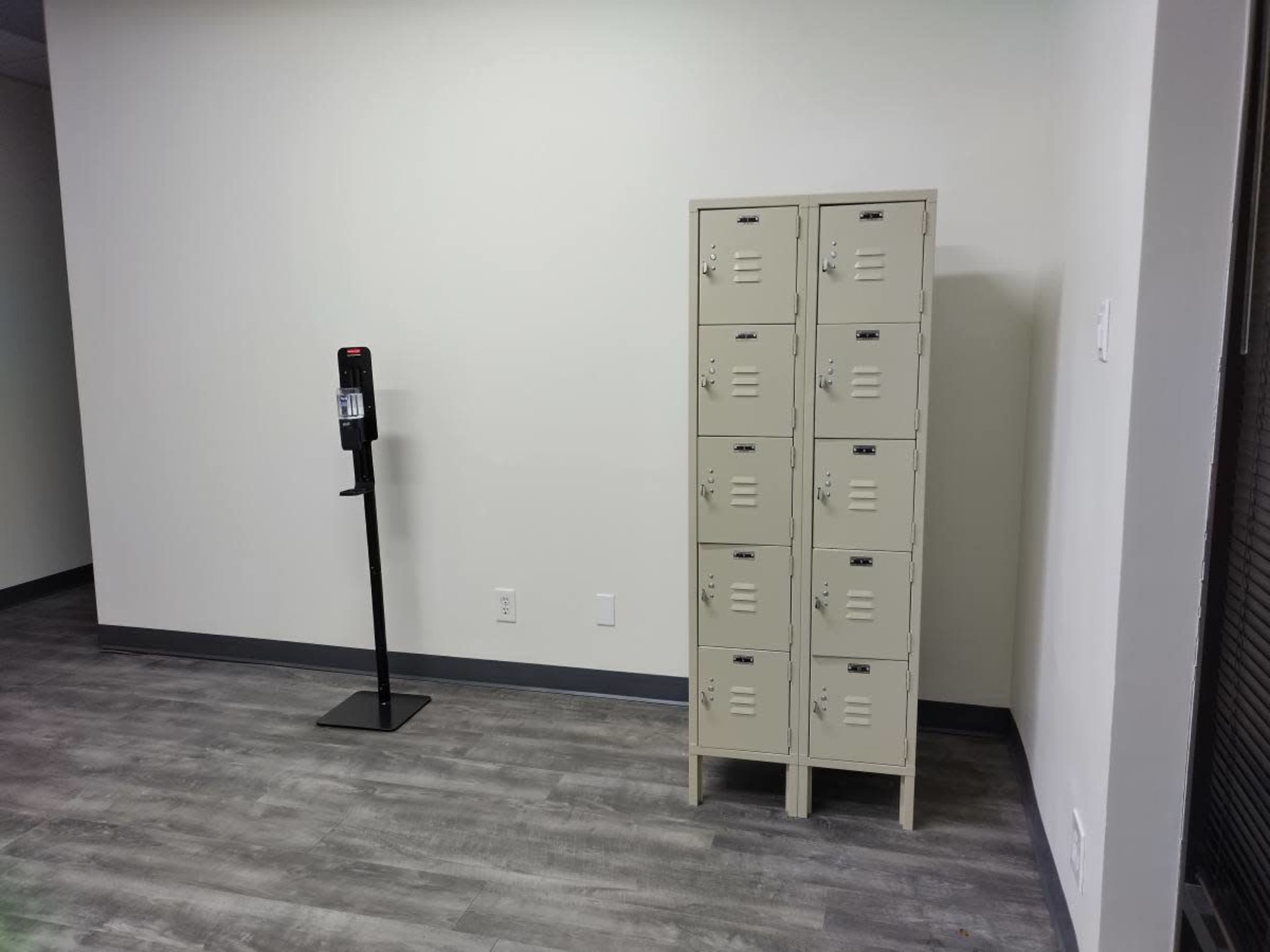 The image shows a small room with a metal locker unit and a coin-operated payphone against a wall, both positioned on a gray floor.