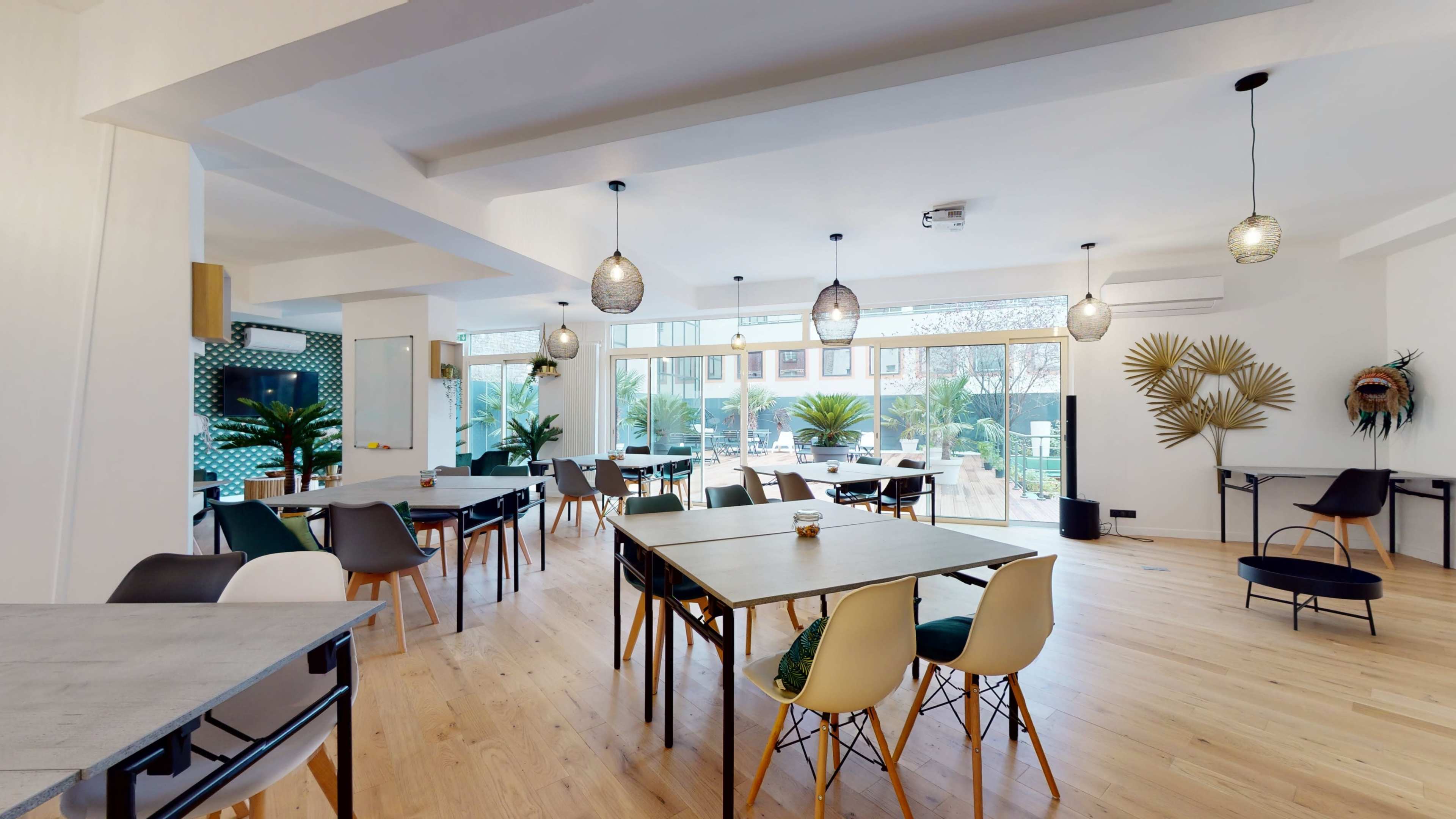 The scene shows a modern dining area with wooden tables and chairs, large windows allowing natural light, and decorative plants in a bright, open space.