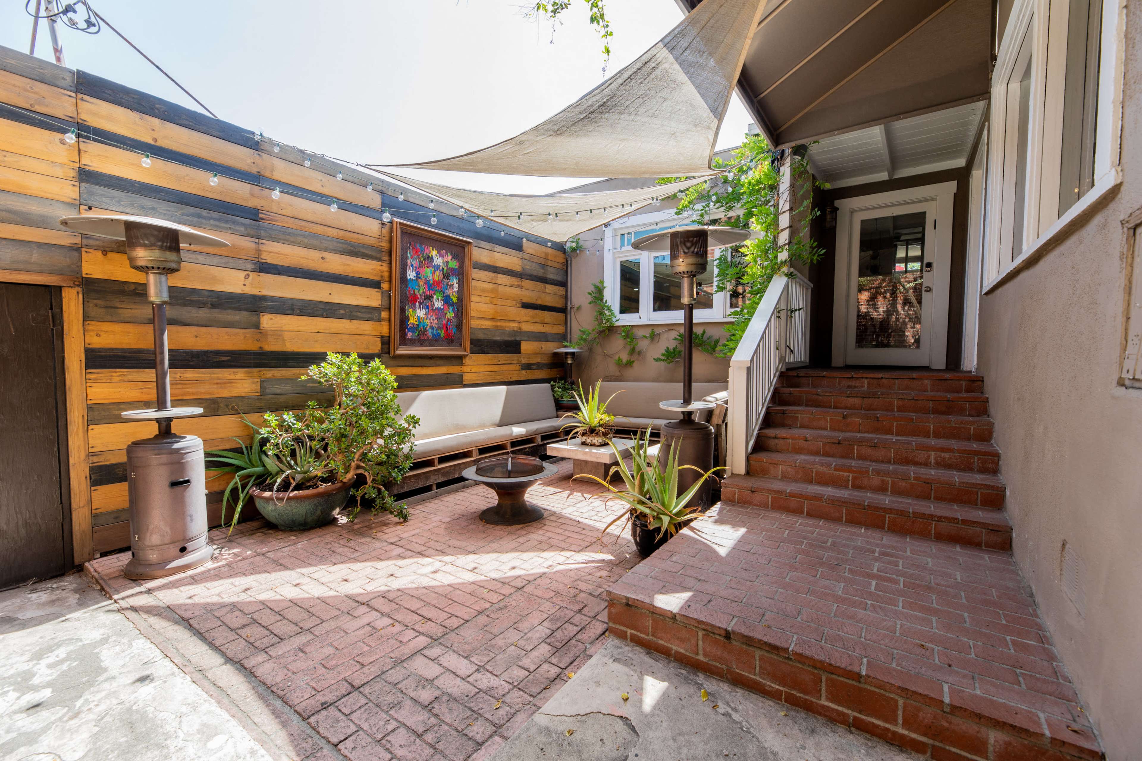 A cozy outdoor patio area featuring a seating arrangement, decorative plants, and a staircase leading to an entrance.