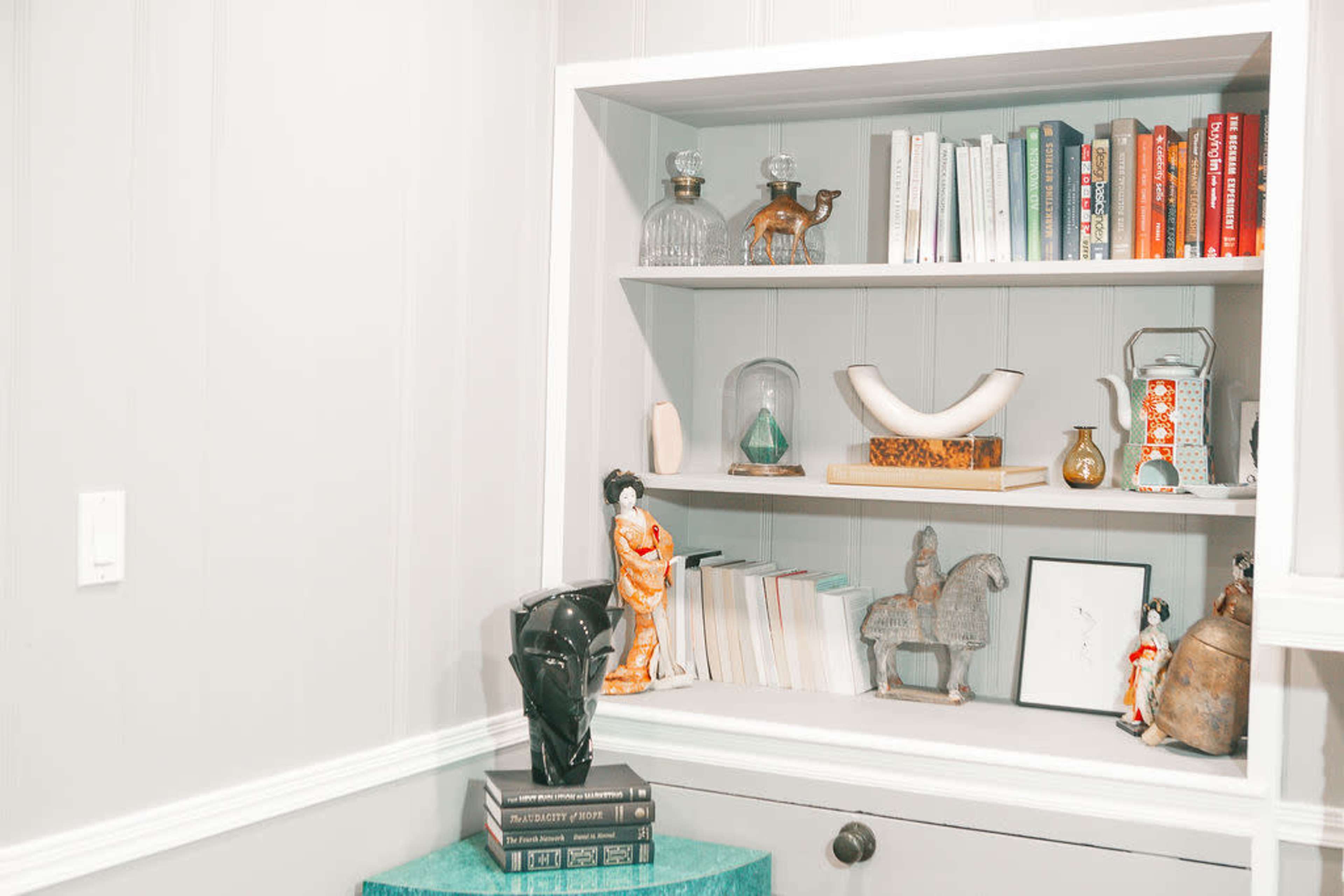 A neatly organized bookshelf filled with various decorative items, books, and sculptures.