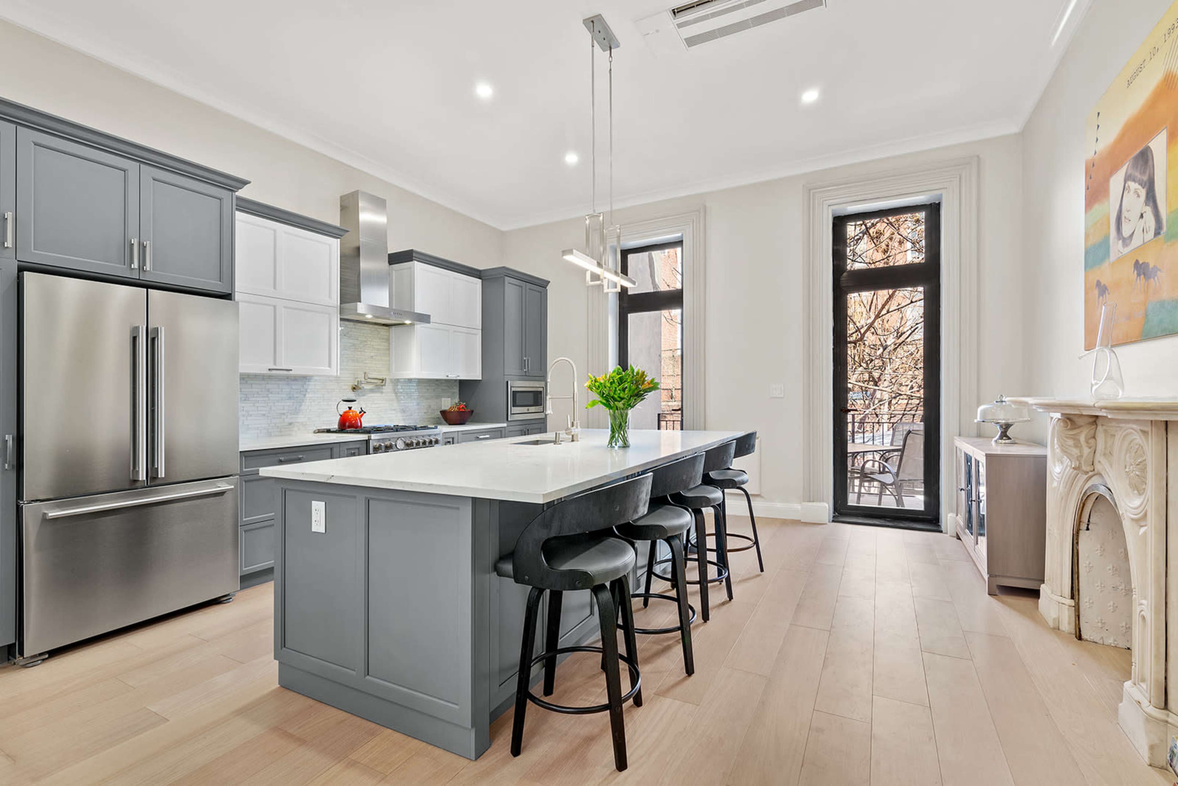 The modern kitchen features gray cabinetry, stainless steel appliances, and a large island with bar seating.