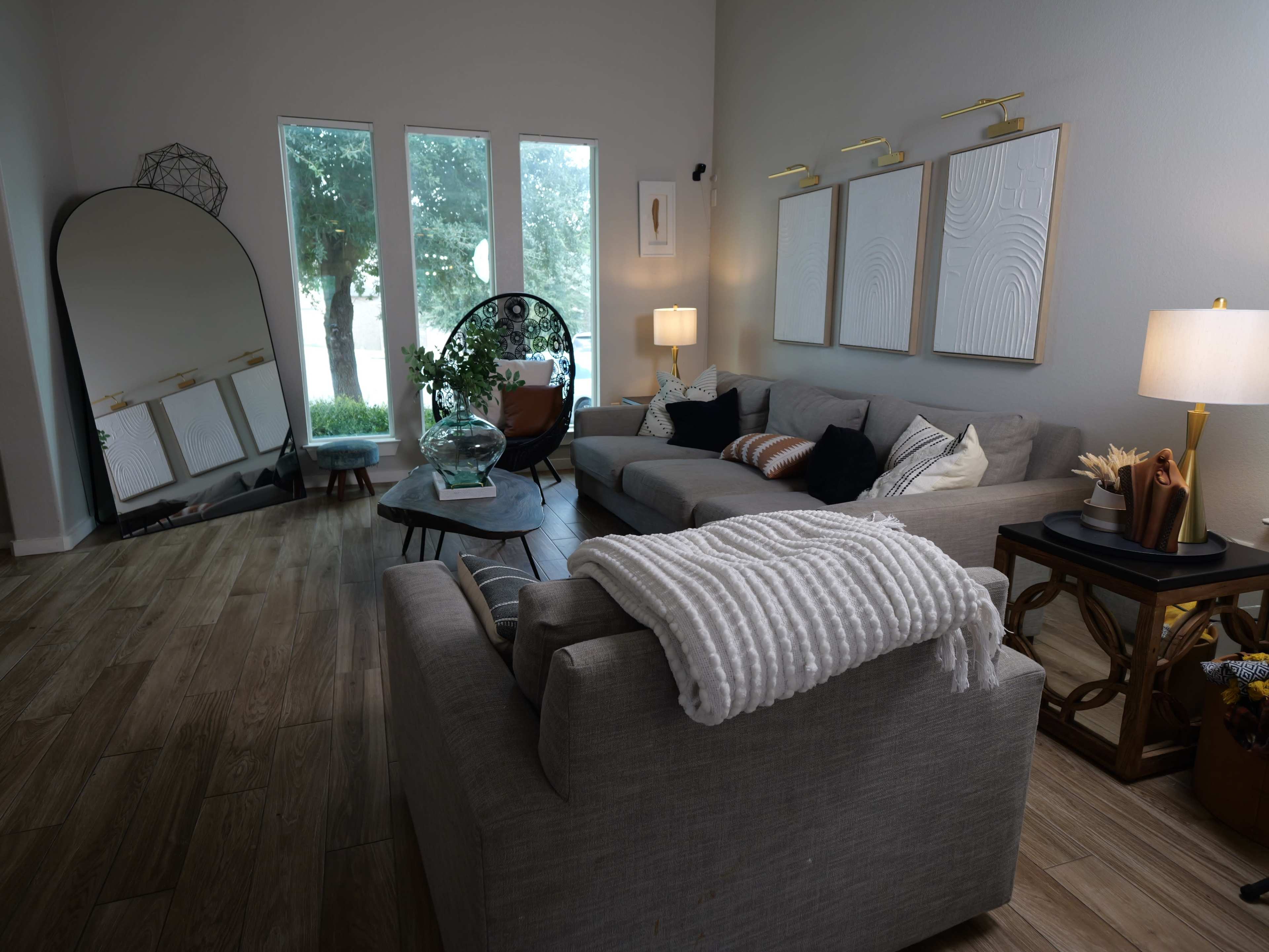 The living room features two sofas, a round coffee table, and large windows that allow natural light to fill the space.