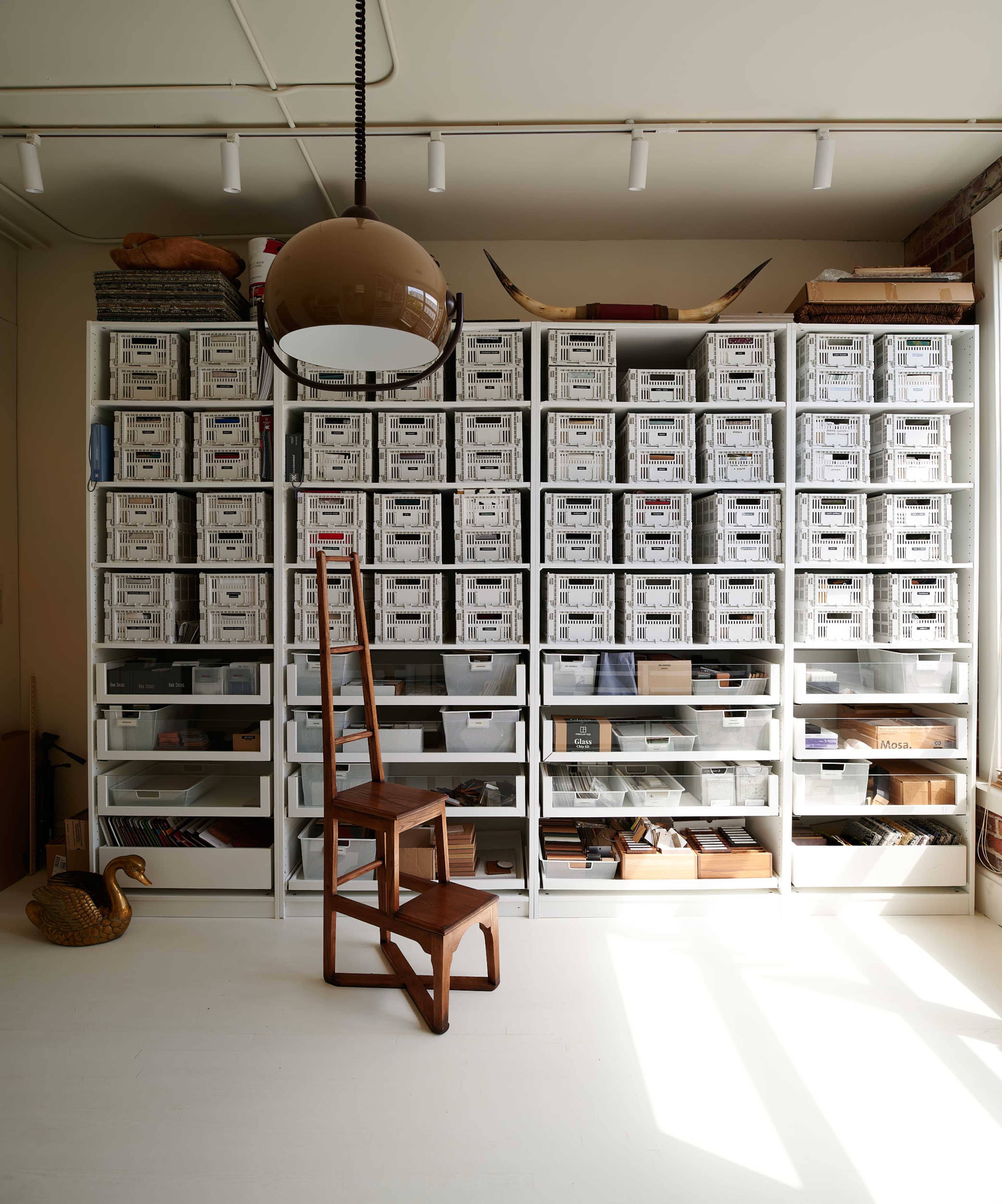 A wooden chair stands in front of a large shelving unit filled with storage boxes and various items.