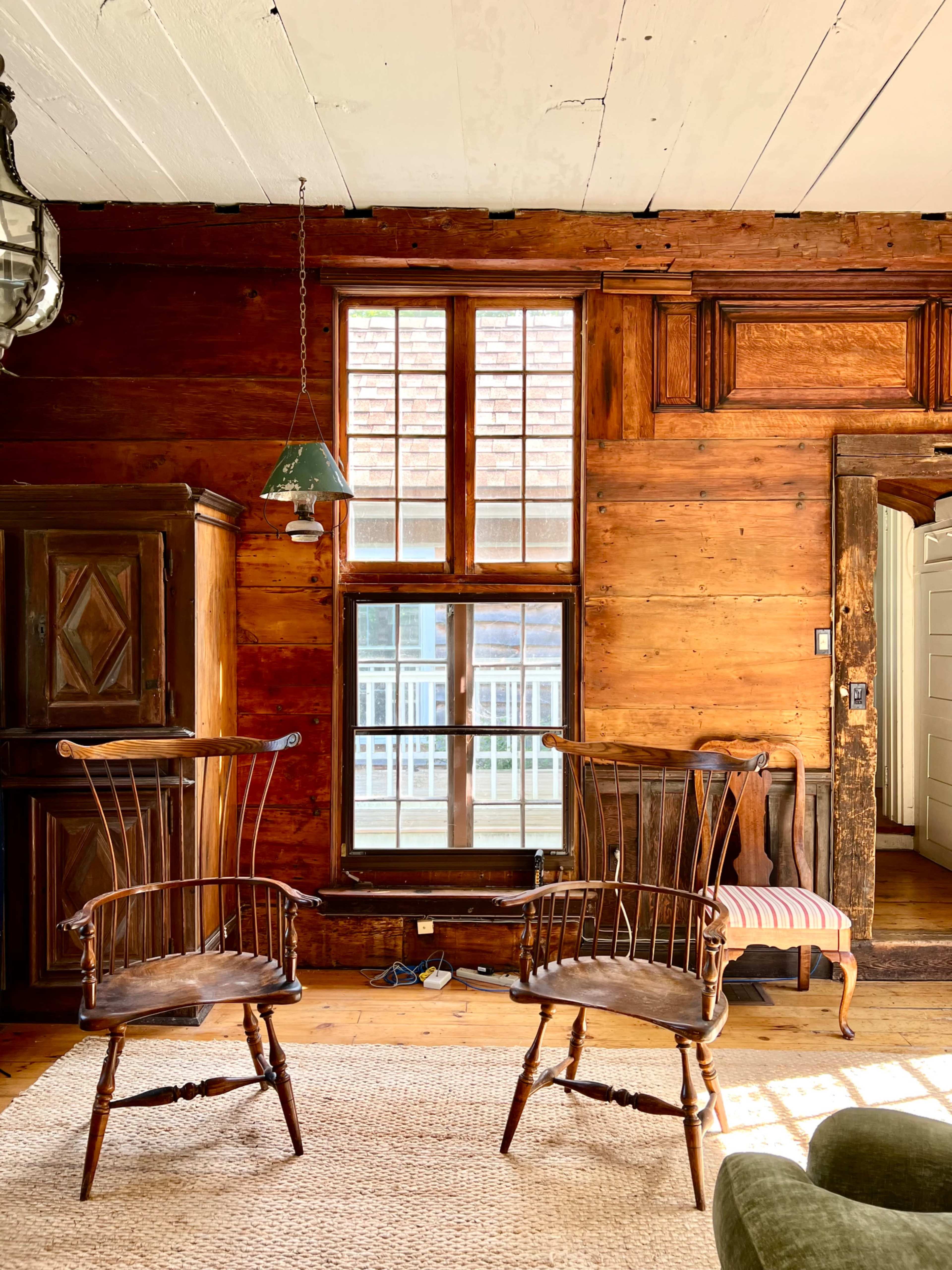 The room features two wooden chairs facing each other, with a window and a wooden door visible in the background.