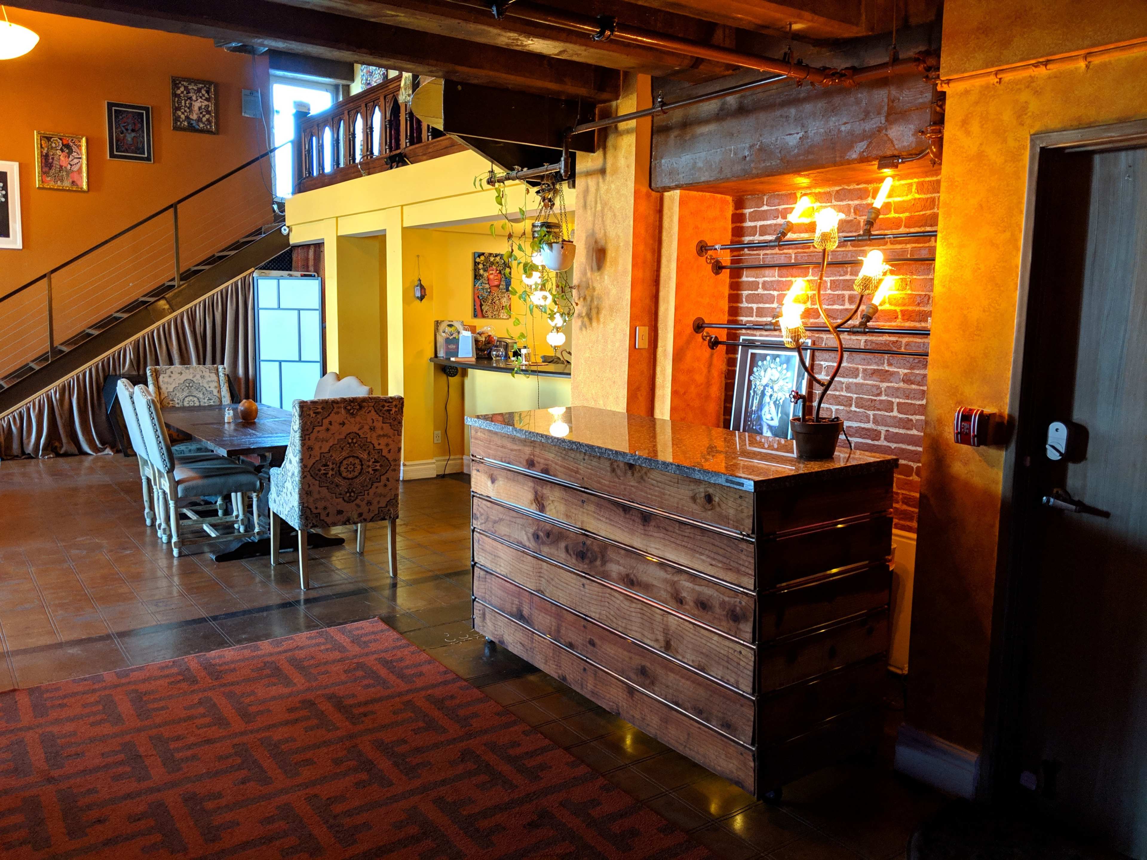 A cozy interior space featuring a wooden reception desk, a seating area with upholstered chairs, and a staircase leading to a second level.