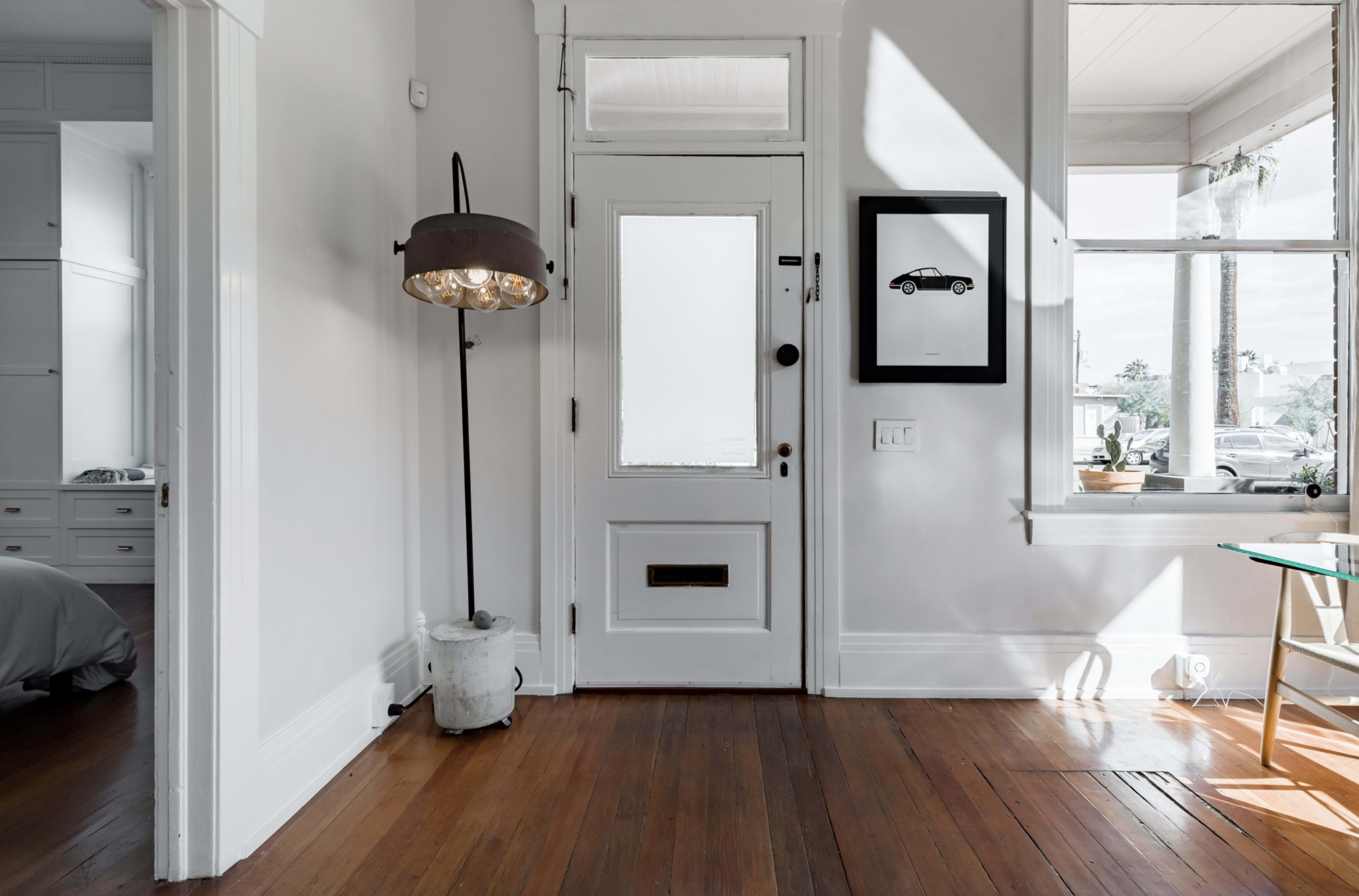 A well-lit entryway featuring a front door, a floor lamp, and a framed picture on the wall.