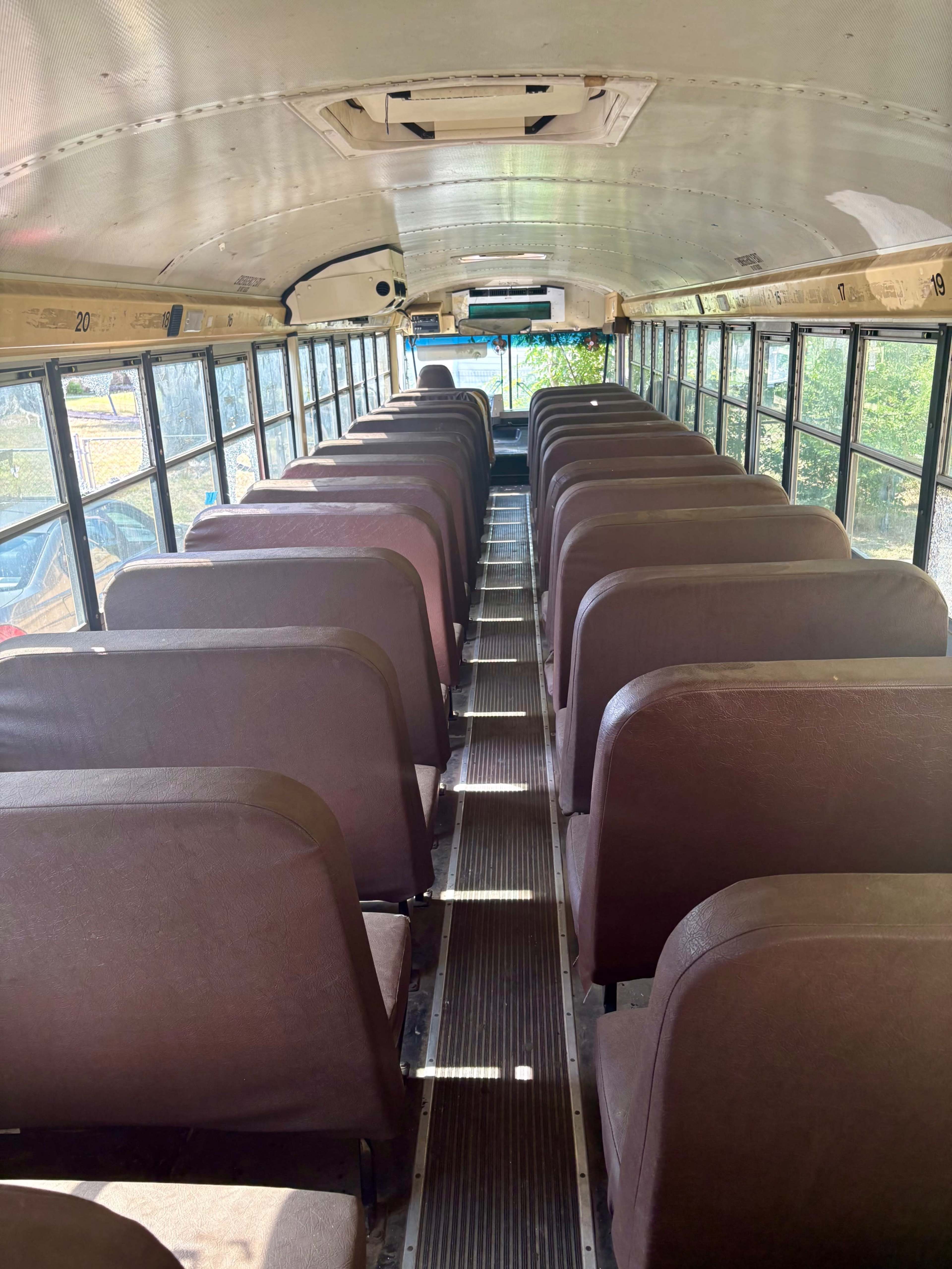 The interior of a school bus features rows of empty seats with a clear aisle running down the center.