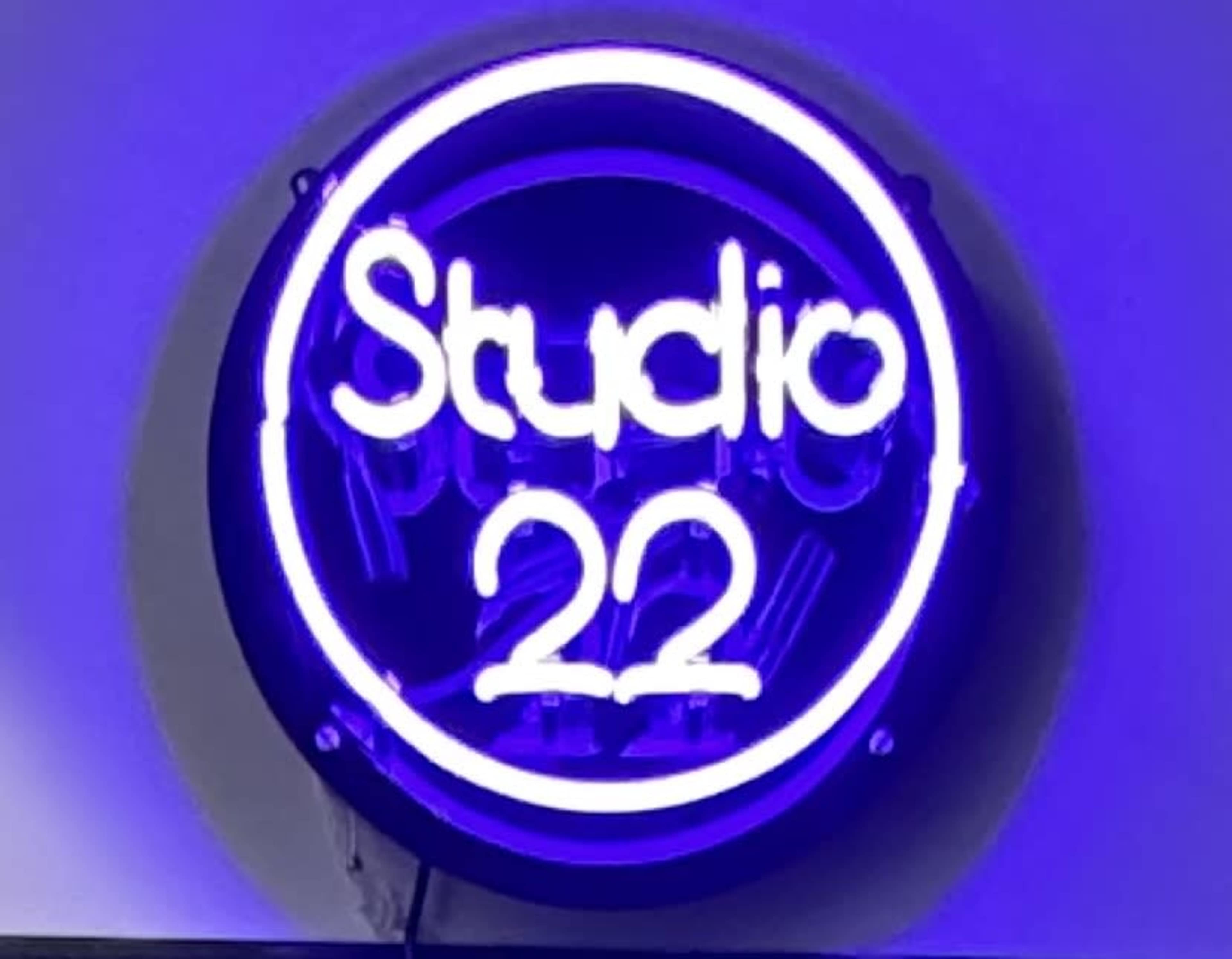A neon sign displaying the words "Studio 22" in glowing white letters against a purple background.