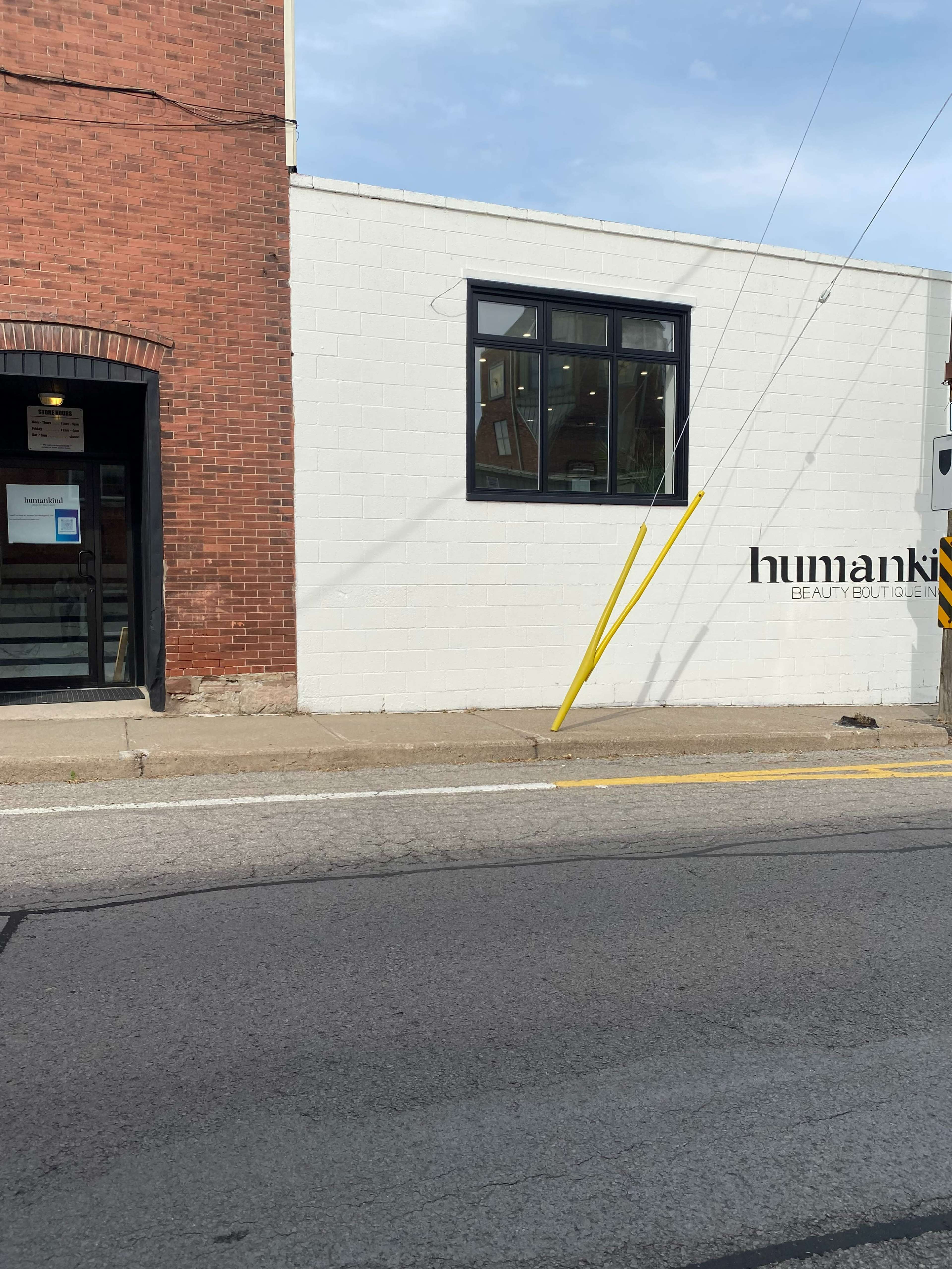 A white building with a large window and the sign "humankind beauty boutique," next to a brick building with a separate entrance.