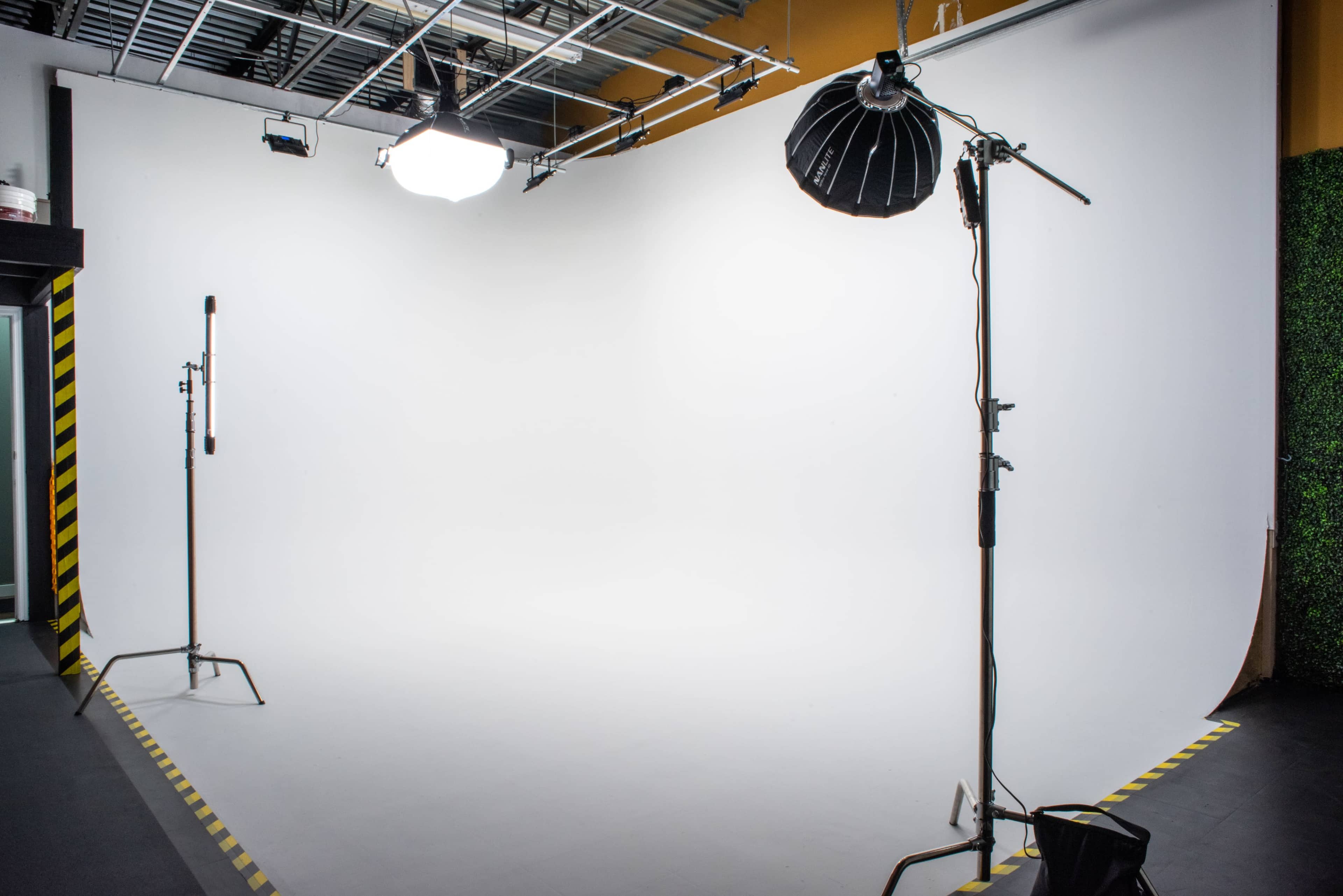 A photography studio with a white backdrop and lighting equipment positioned on stands.