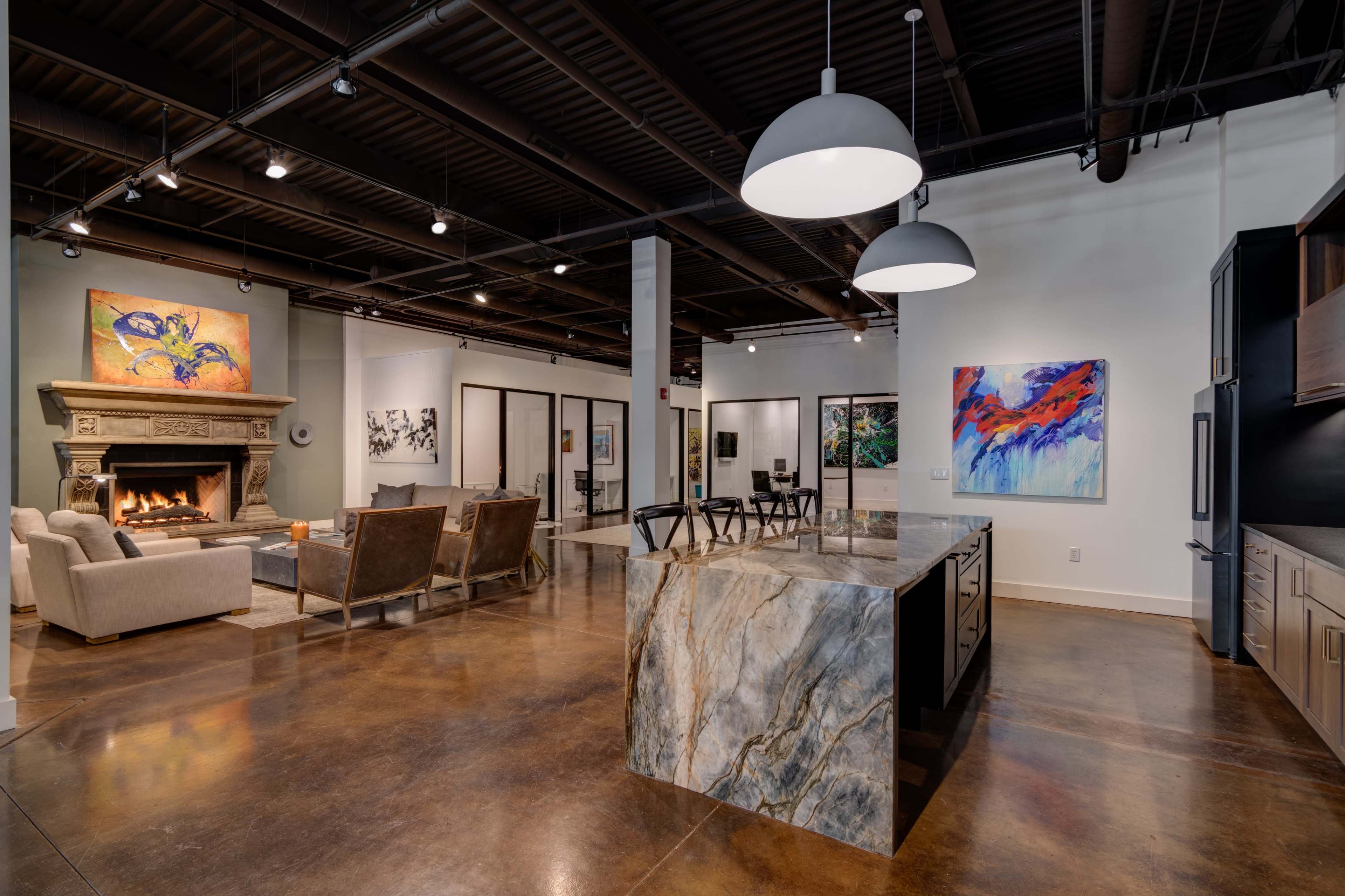 A spacious open-concept living area with a modern kitchen featuring a large island and a cozy seating area around a fireplace.