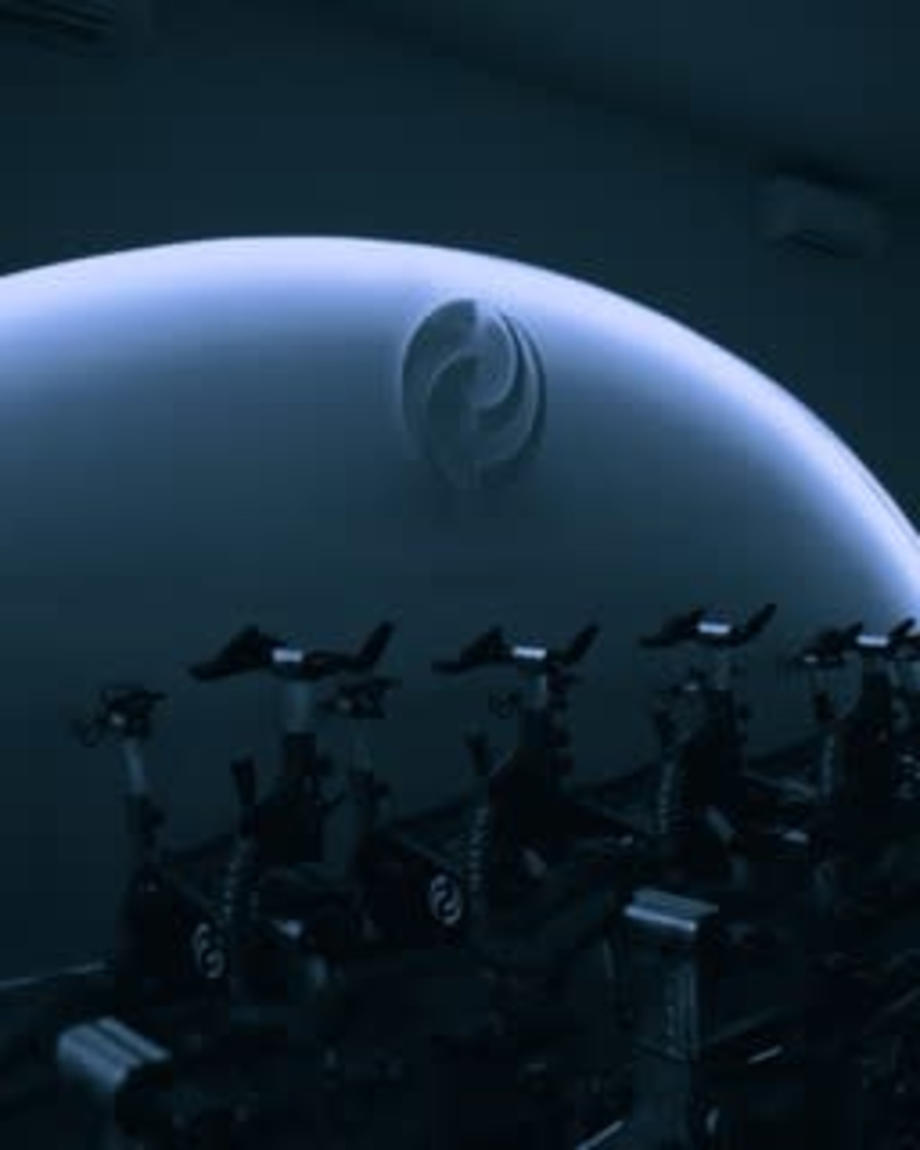 The image shows a row of stationary bicycles under a softly illuminated curved structure featuring a logo.