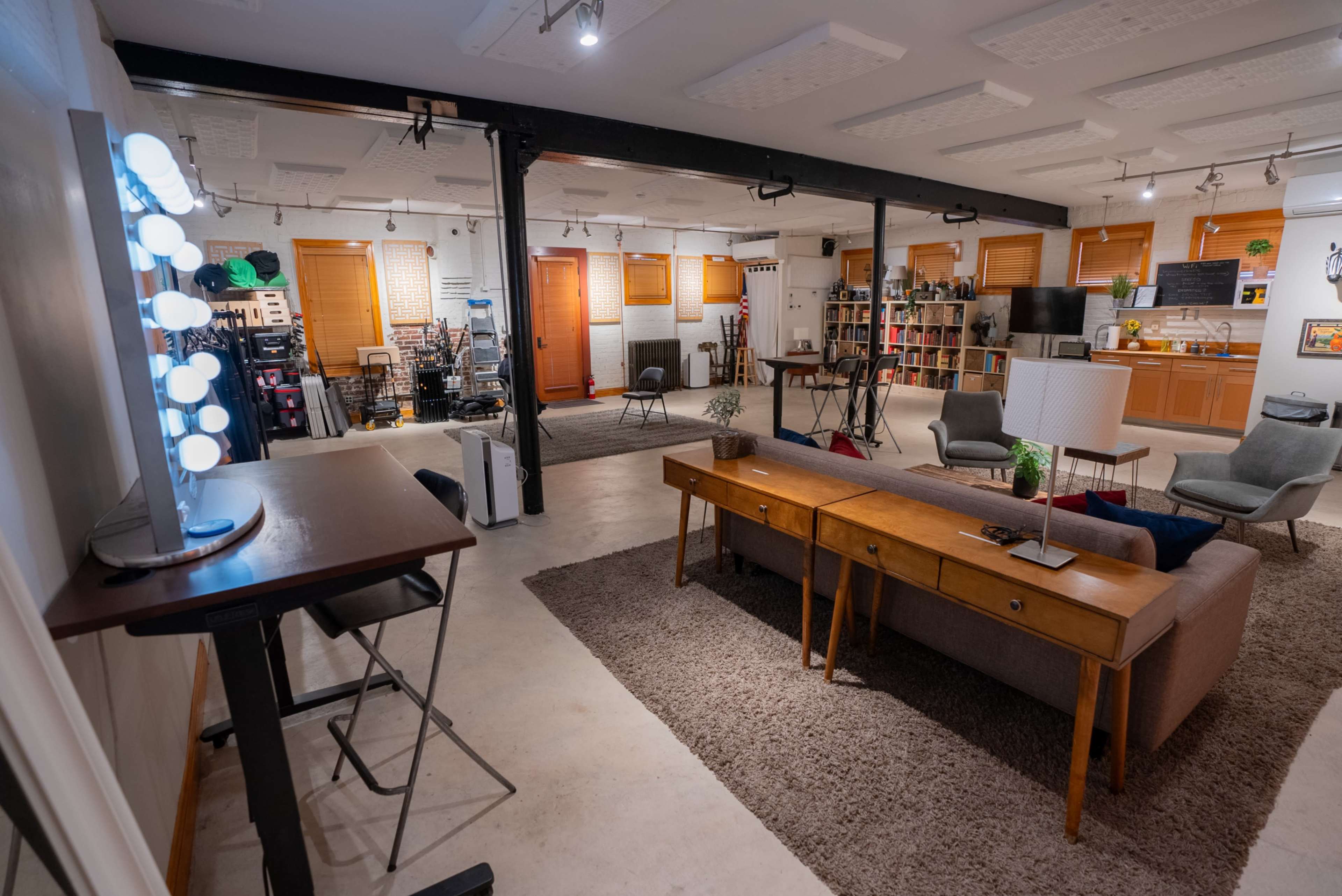 A spacious, well-lit room featuring a seating area with a sofa and chairs, a coffee table, and shelving filled with various items.