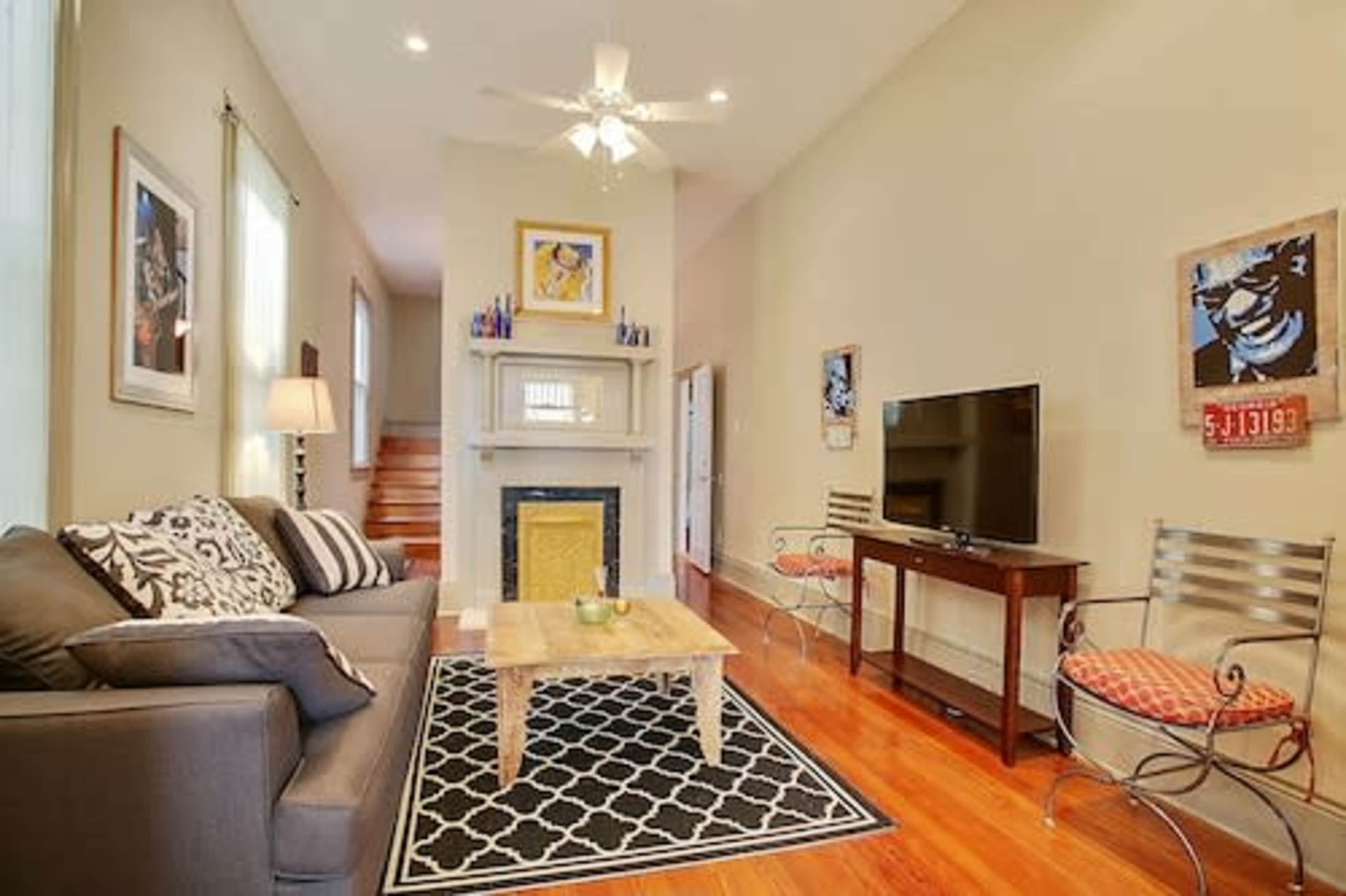 A living room with a sofa, a coffee table, a television, and decorative artwork on the walls.