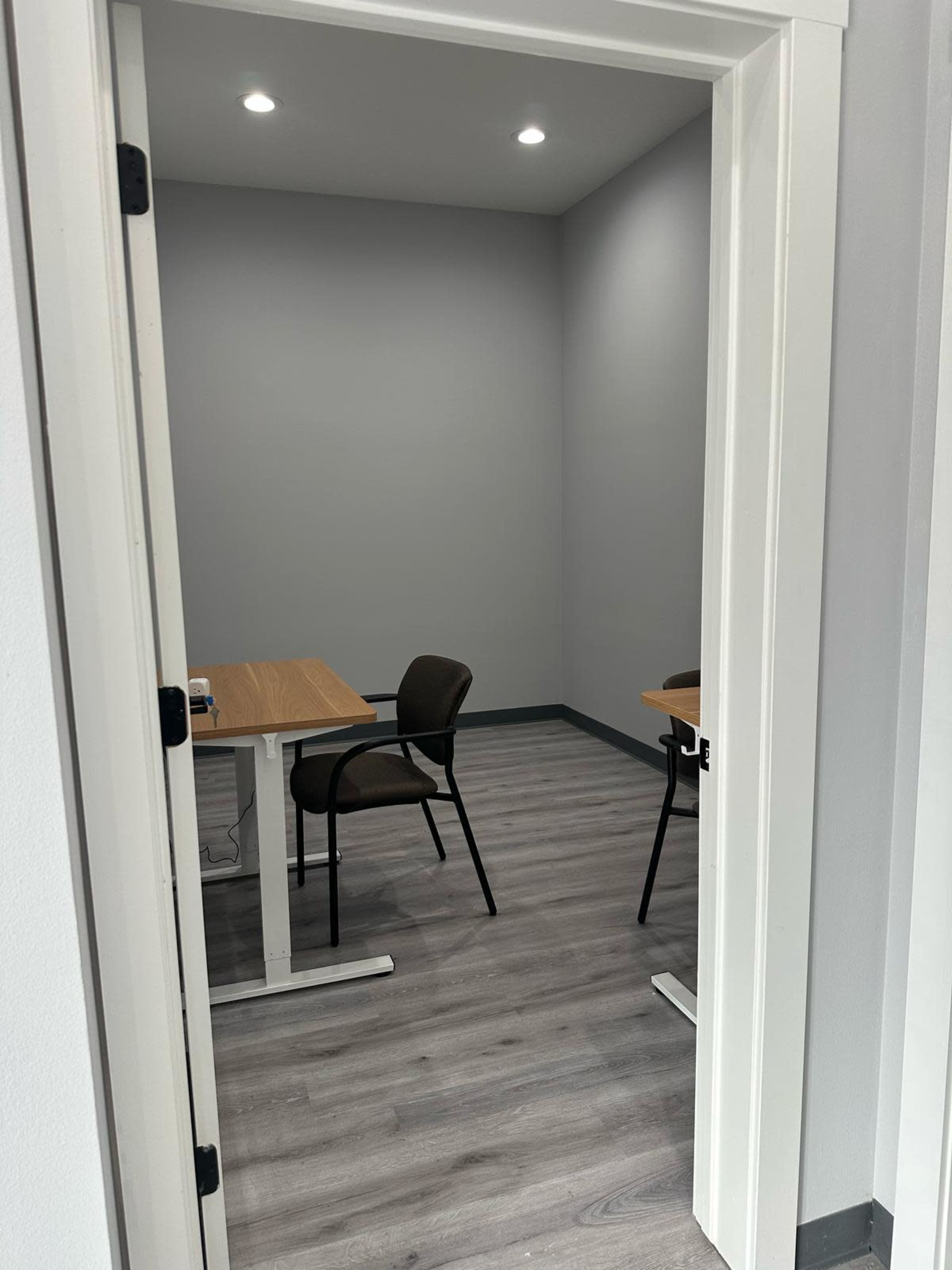 The image shows the interior of a small room with two tables and chairs, viewed through an open door.