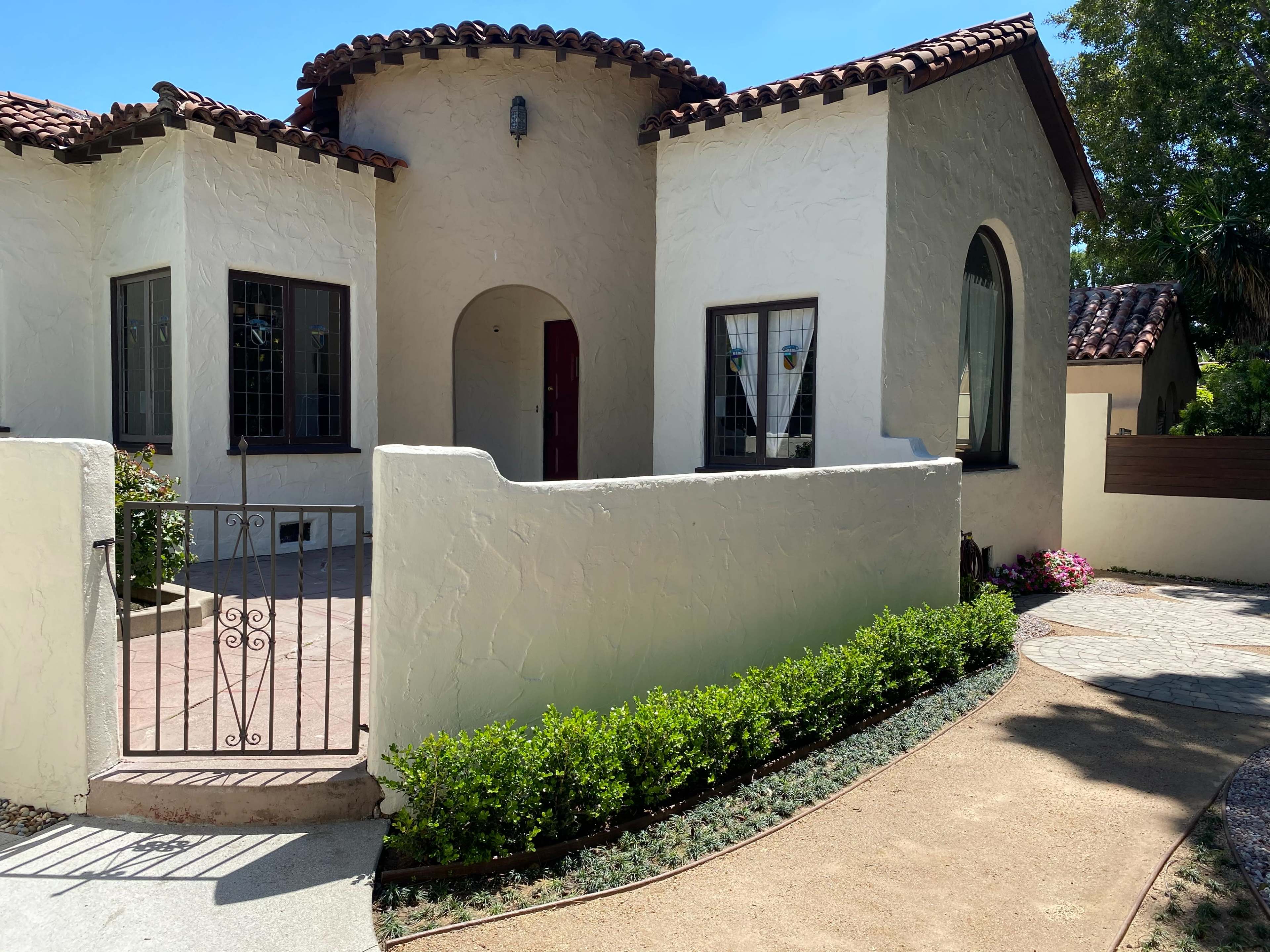 A single-story house with a stucco exterior, a tiled roof, and a landscaped pathway leading to the entrance.