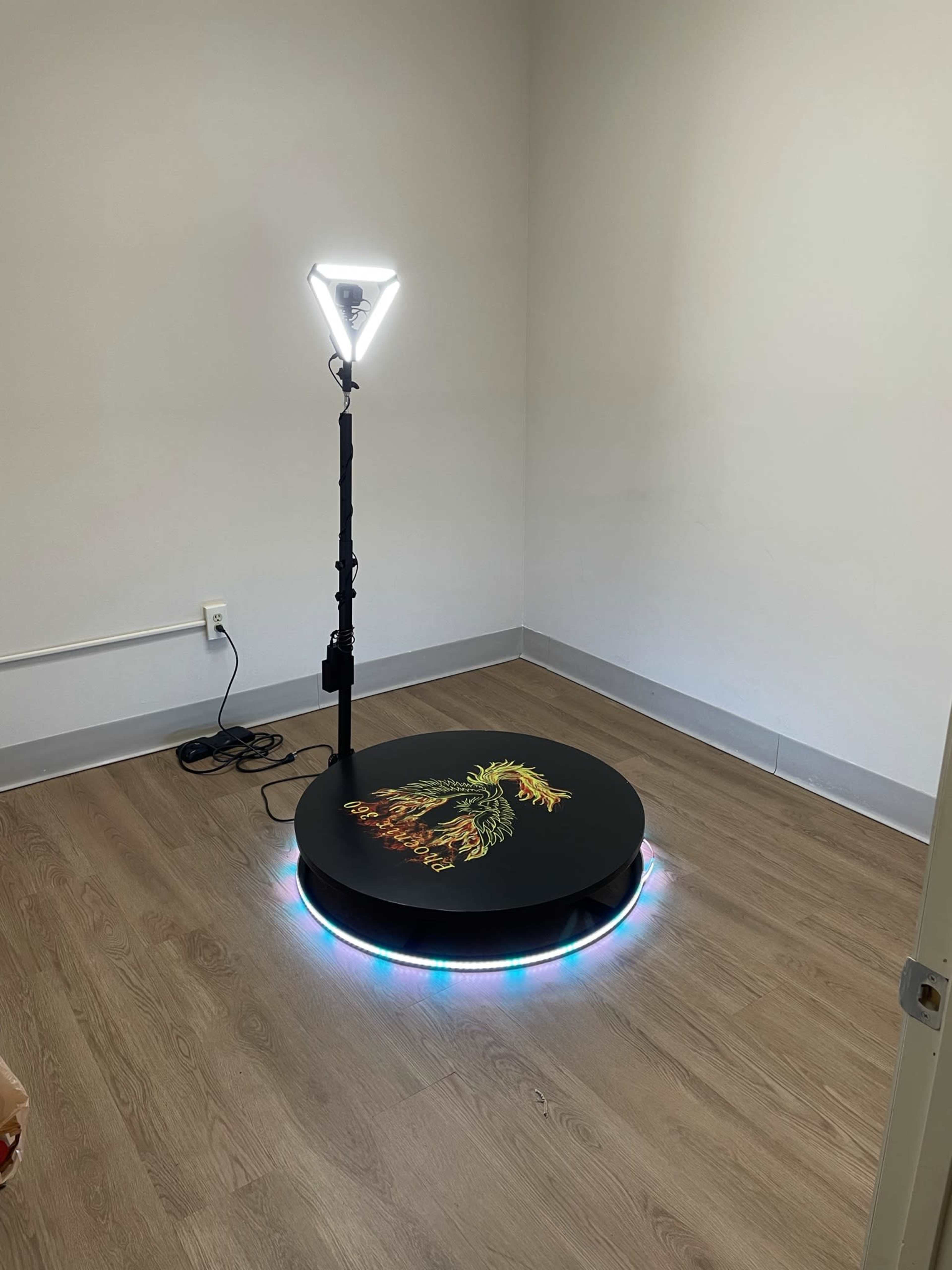 A small, empty room featuring a circular platform with colorful lighting and a lamp on a stand.