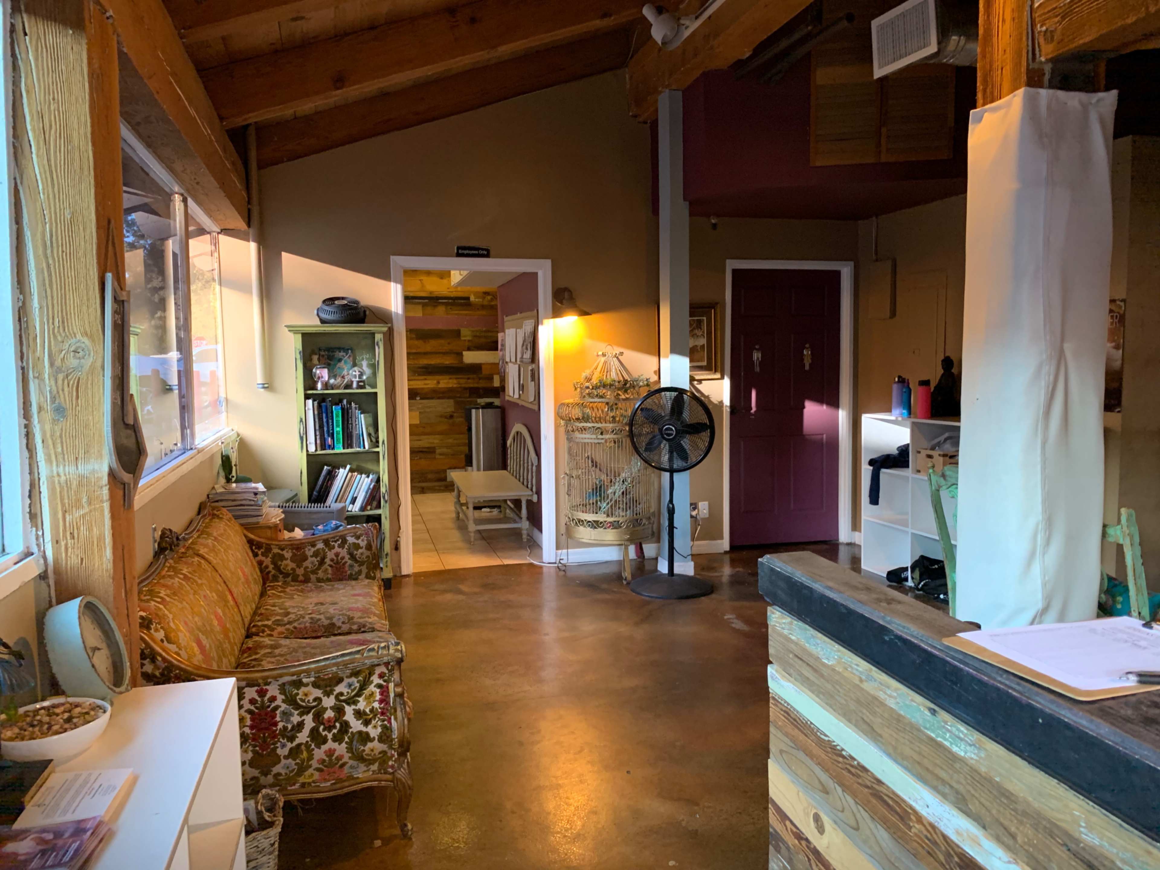 A cozy interior space with a patterned sofa, wooden beams, and a purple door leading to another room.
