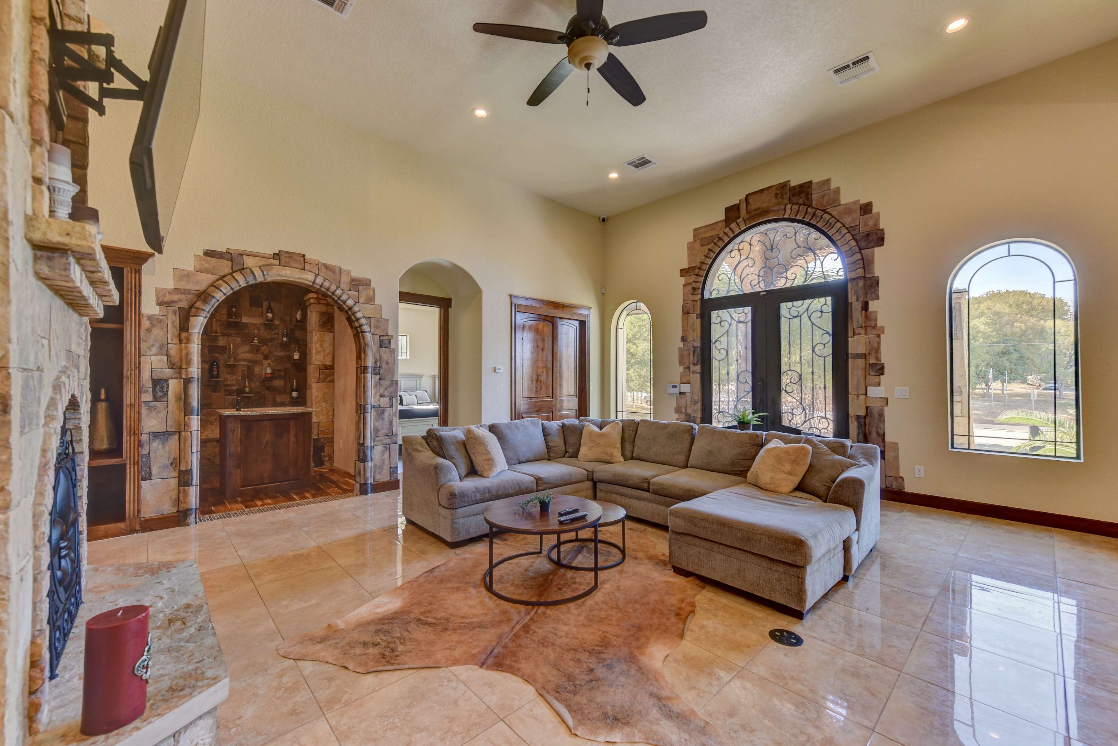 A spacious living room with a large sectional sofa, a coffee table, and stone archways leading to adjacent areas.