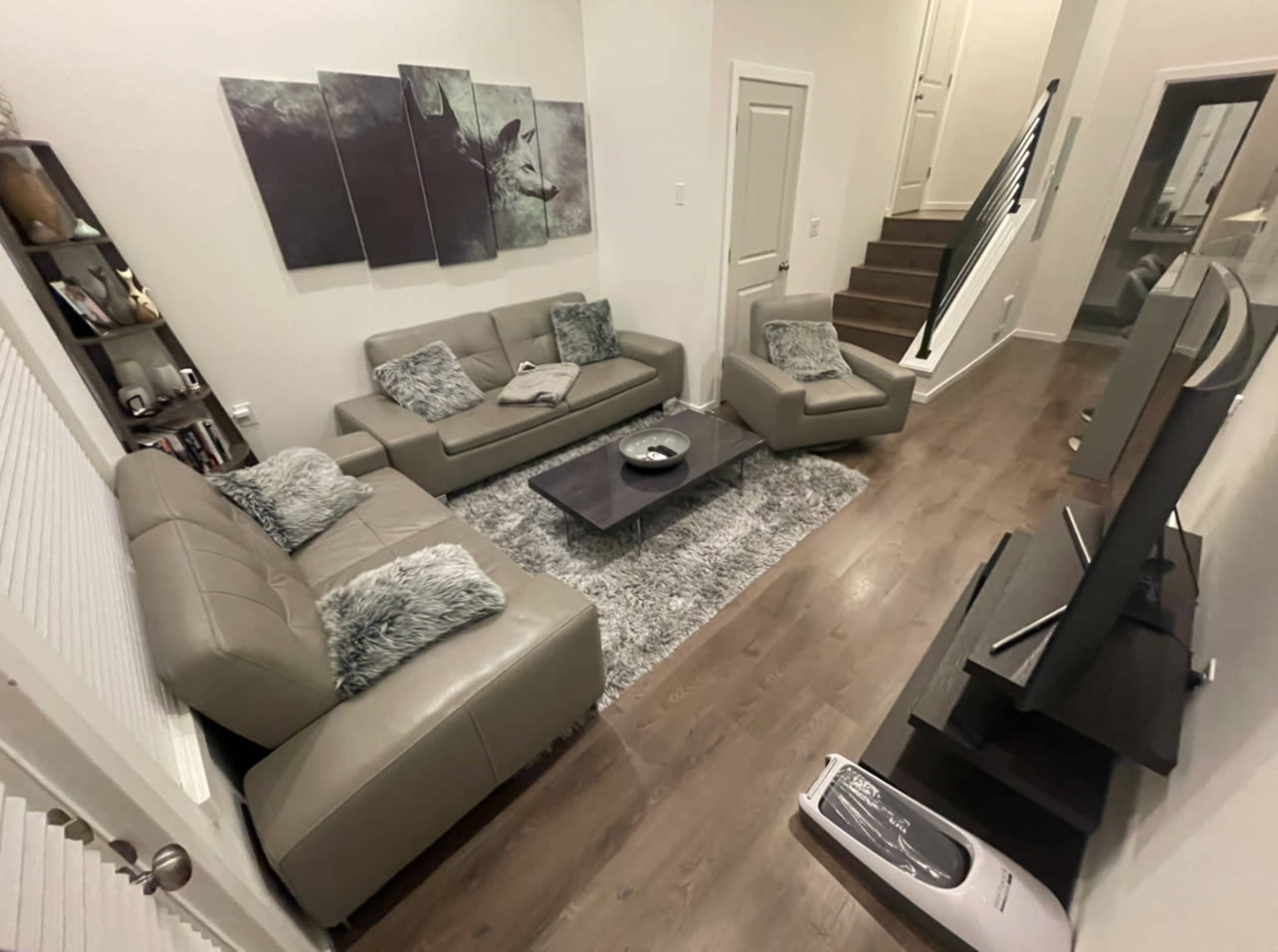 A modern living room featuring two light gray sofas, a coffee table in the center, and a staircase in the background.