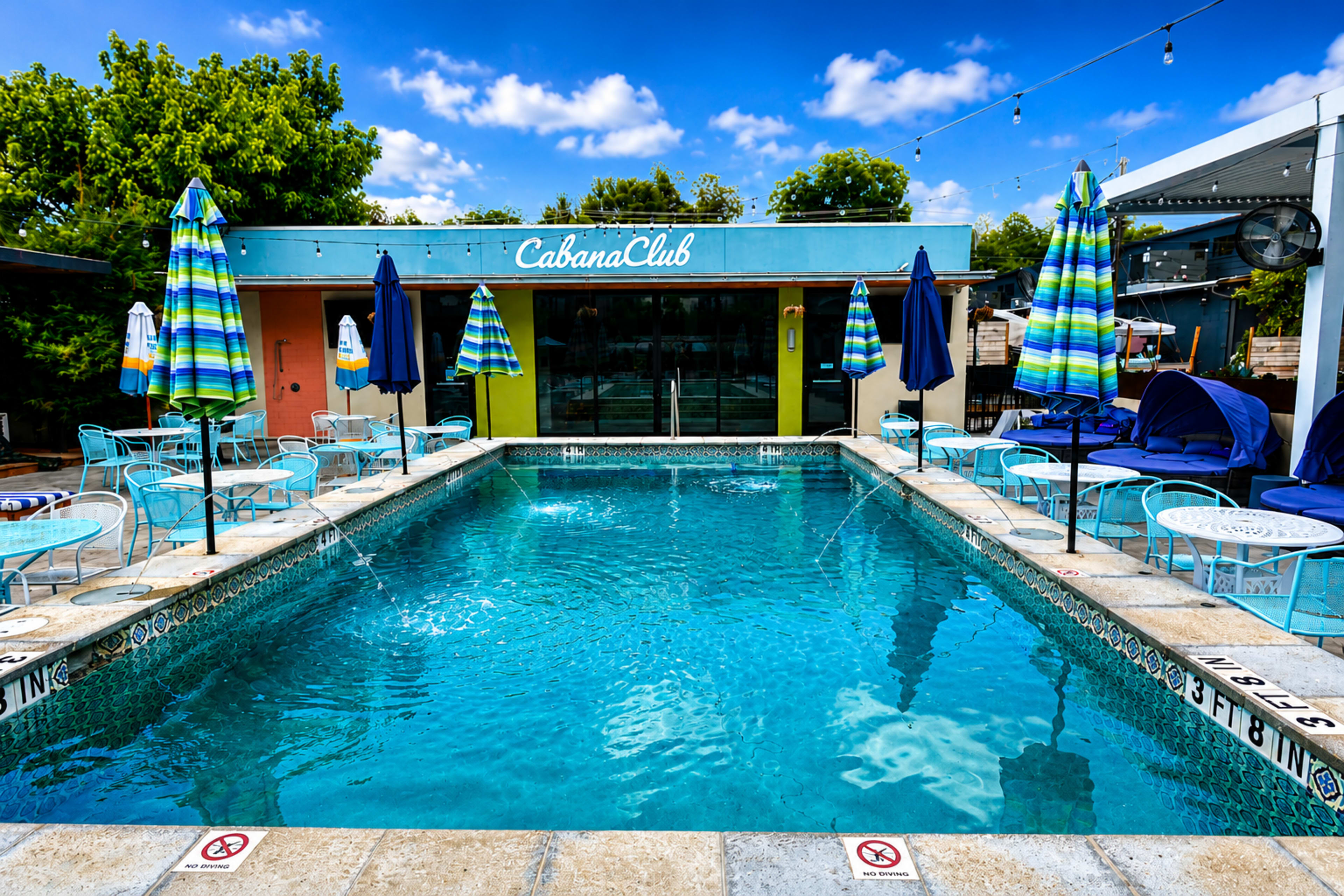 The image shows a swimming pool surrounded by lounge chairs and umbrellas, with a building labeled "Cabana Club" in the background.